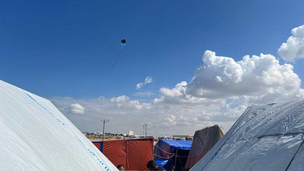 Cheerful kites bobbing on the air’s currents belie the loss and sadness they fly over