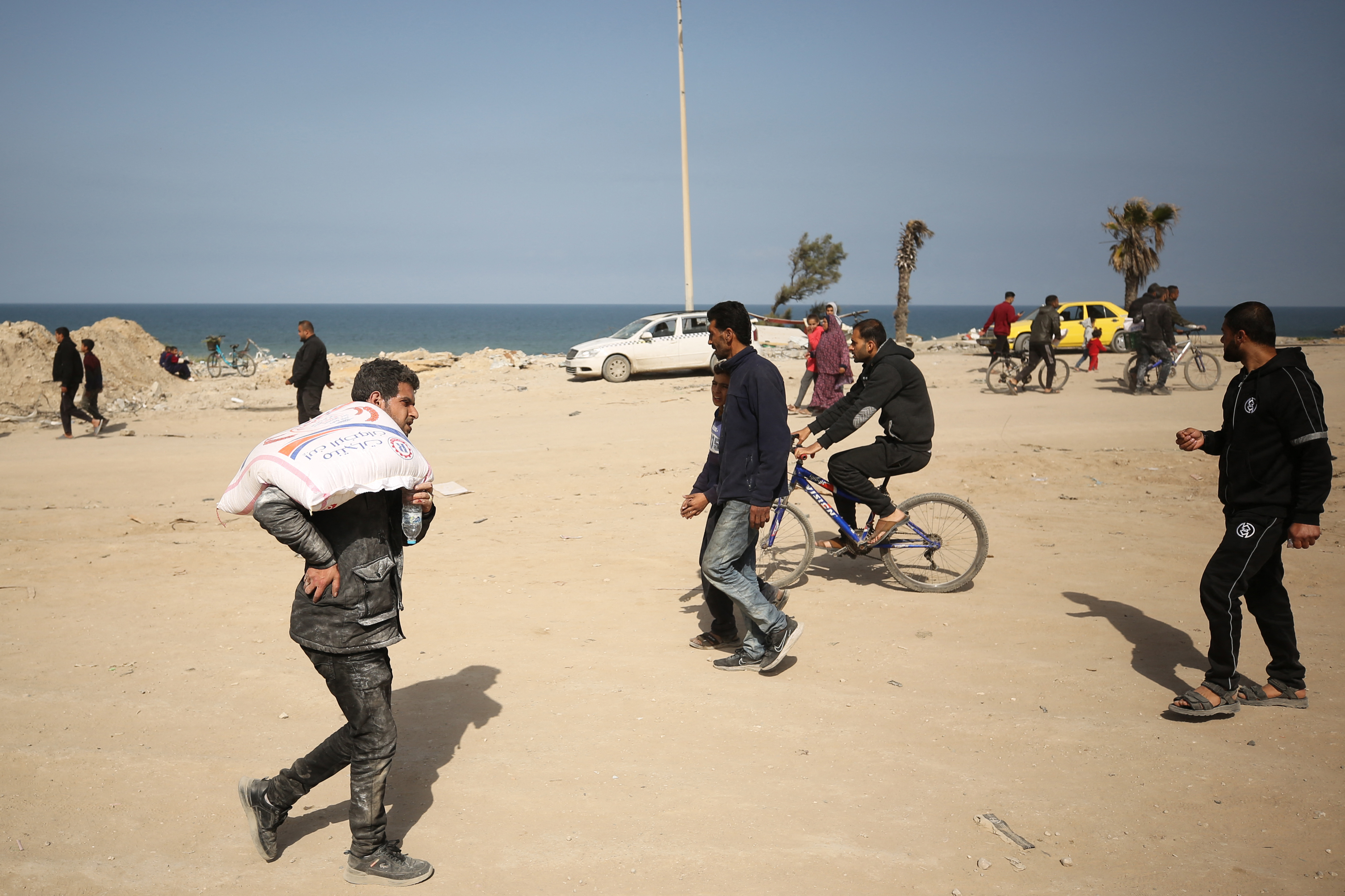 Palestinians transport bags of flour as humanitarian aid arrives in Gaza City on March 6, 2024. [AFP]