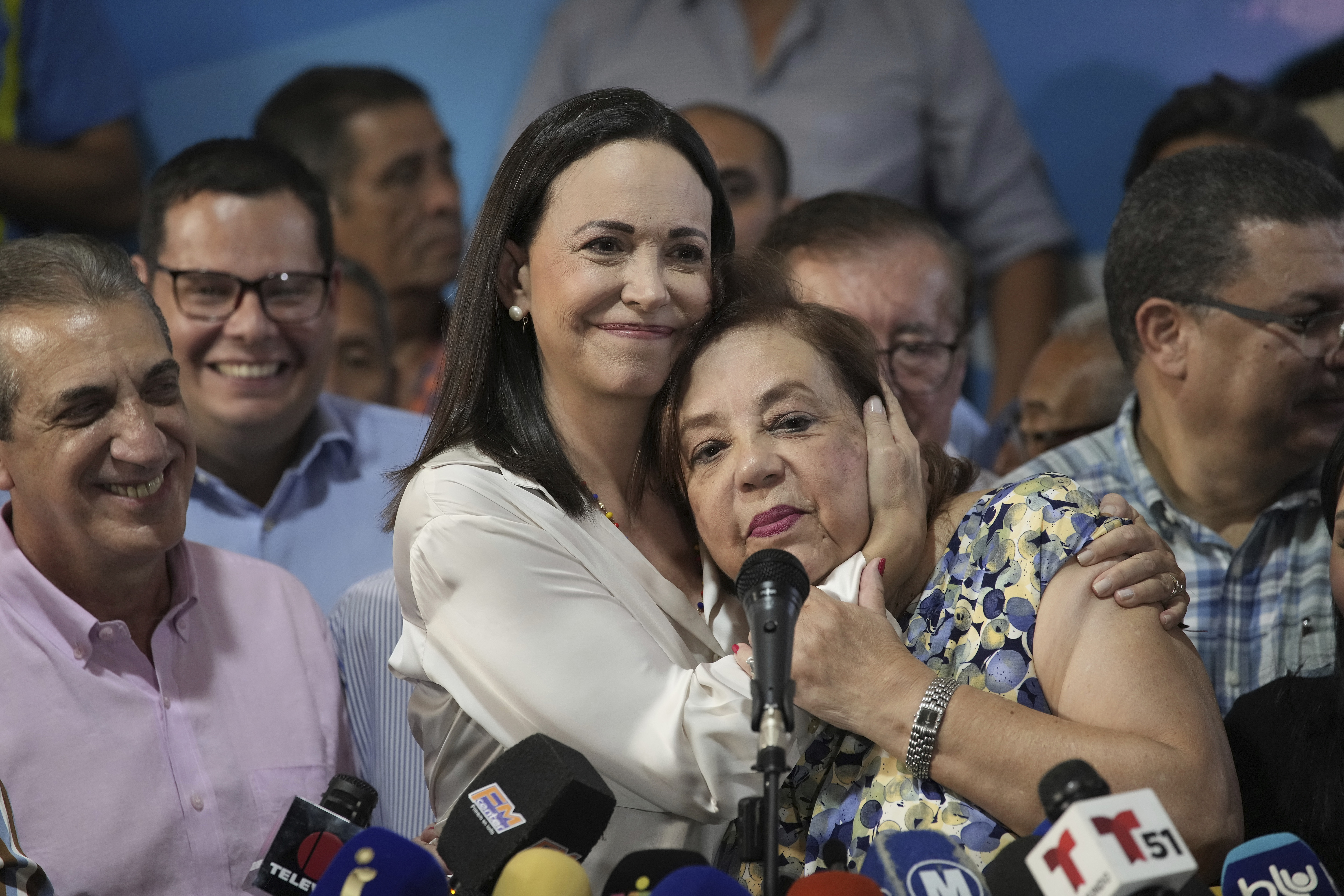 Maria Corina Machado hugs the face of Corina Yoris at a press conference.