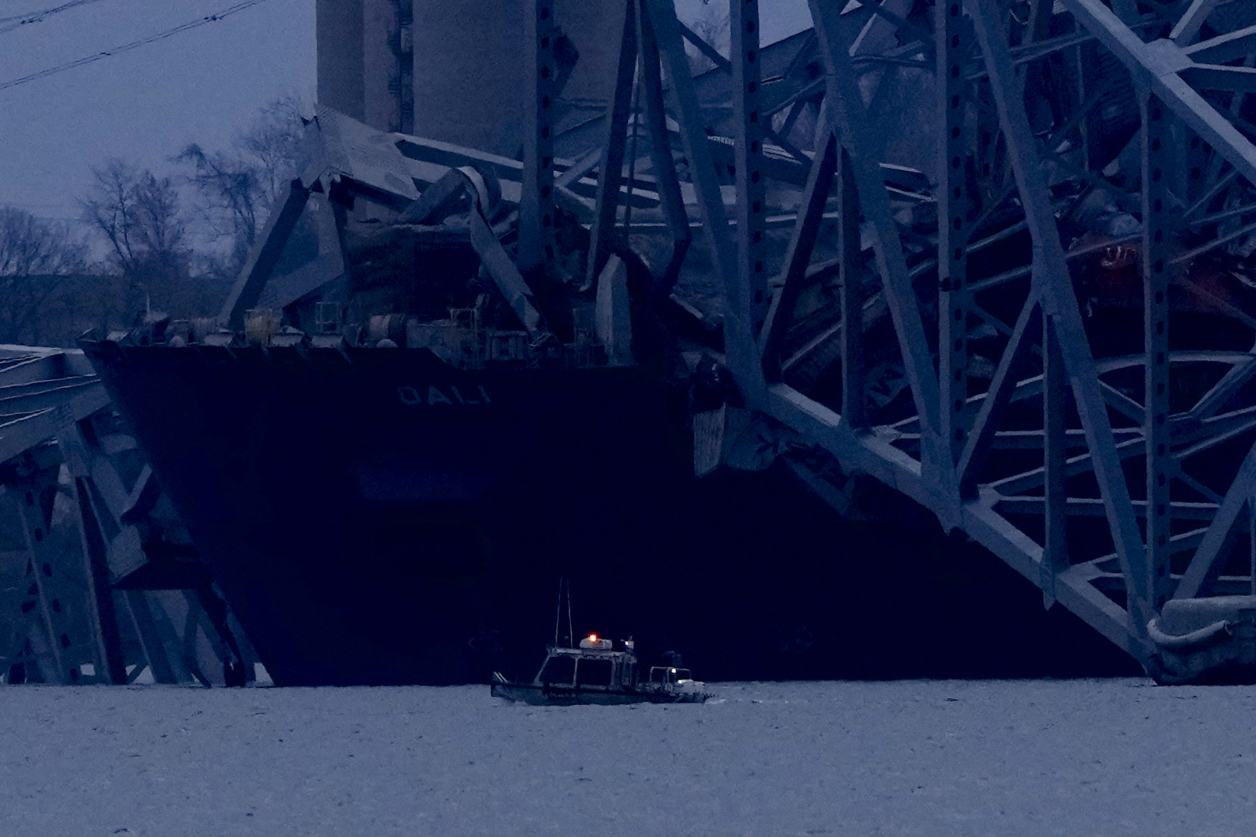 A container ship rests against the wreckage of the Francis Scott Key Bridge as night falls on Tuesday