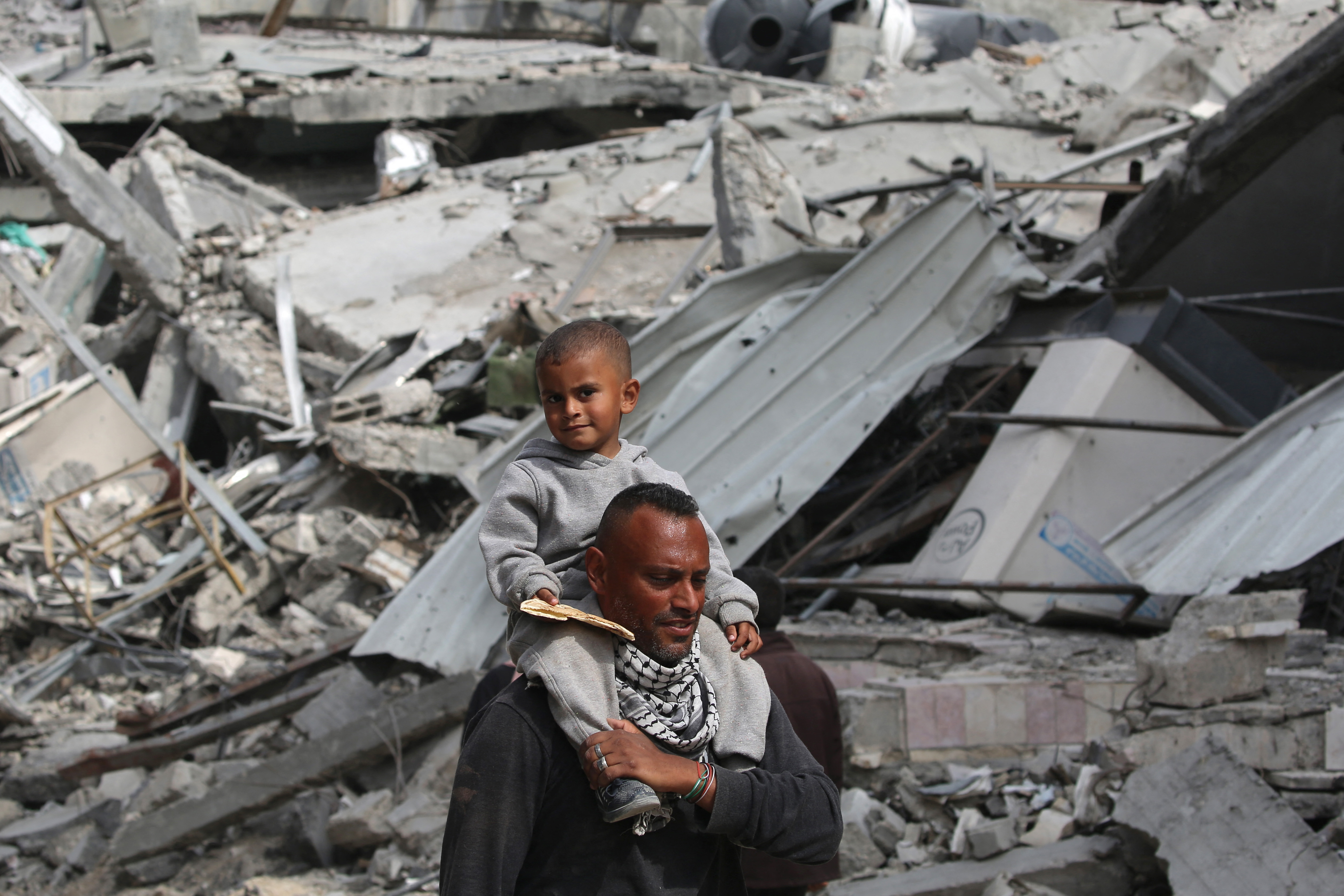 A Palestinian man carries his child on his shoulders