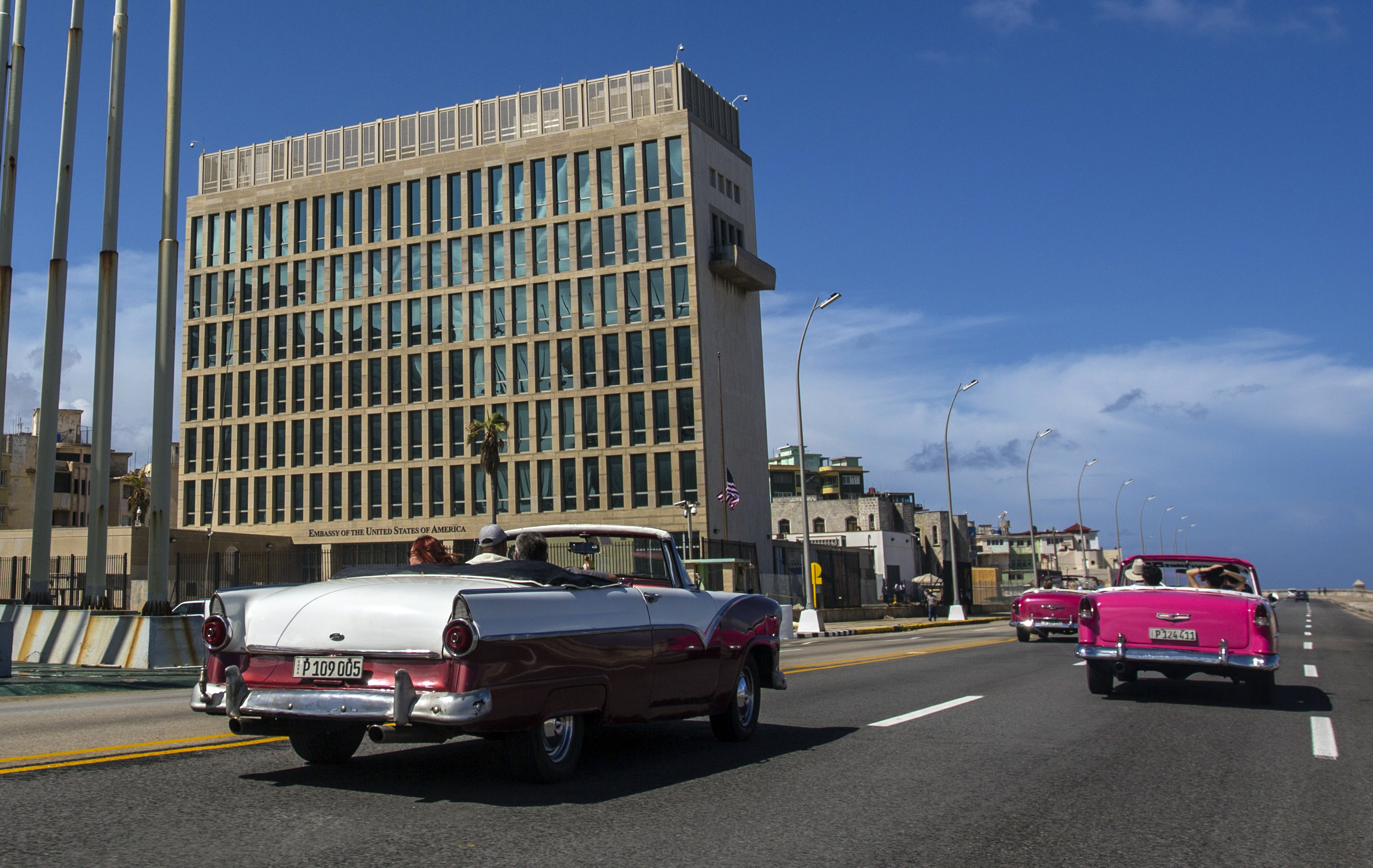 An old-fashioned convertible rolls past the US Embassy in Havana, Cuba.