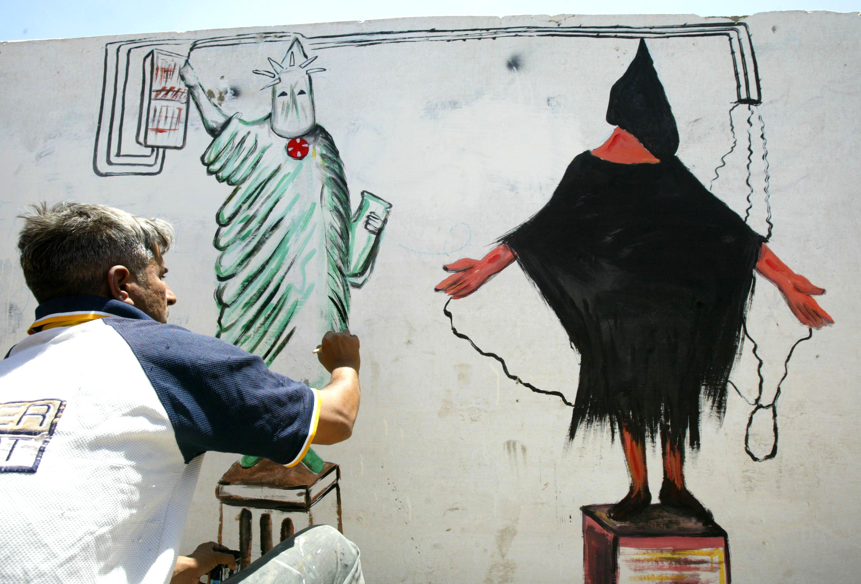 Iraqi artist Salaheddin al-Sallat creates a mural depicting the prisoner abuse at Abu Ghraib prison on the main street of al-Sadr, Baghdad, on May 23, 2004