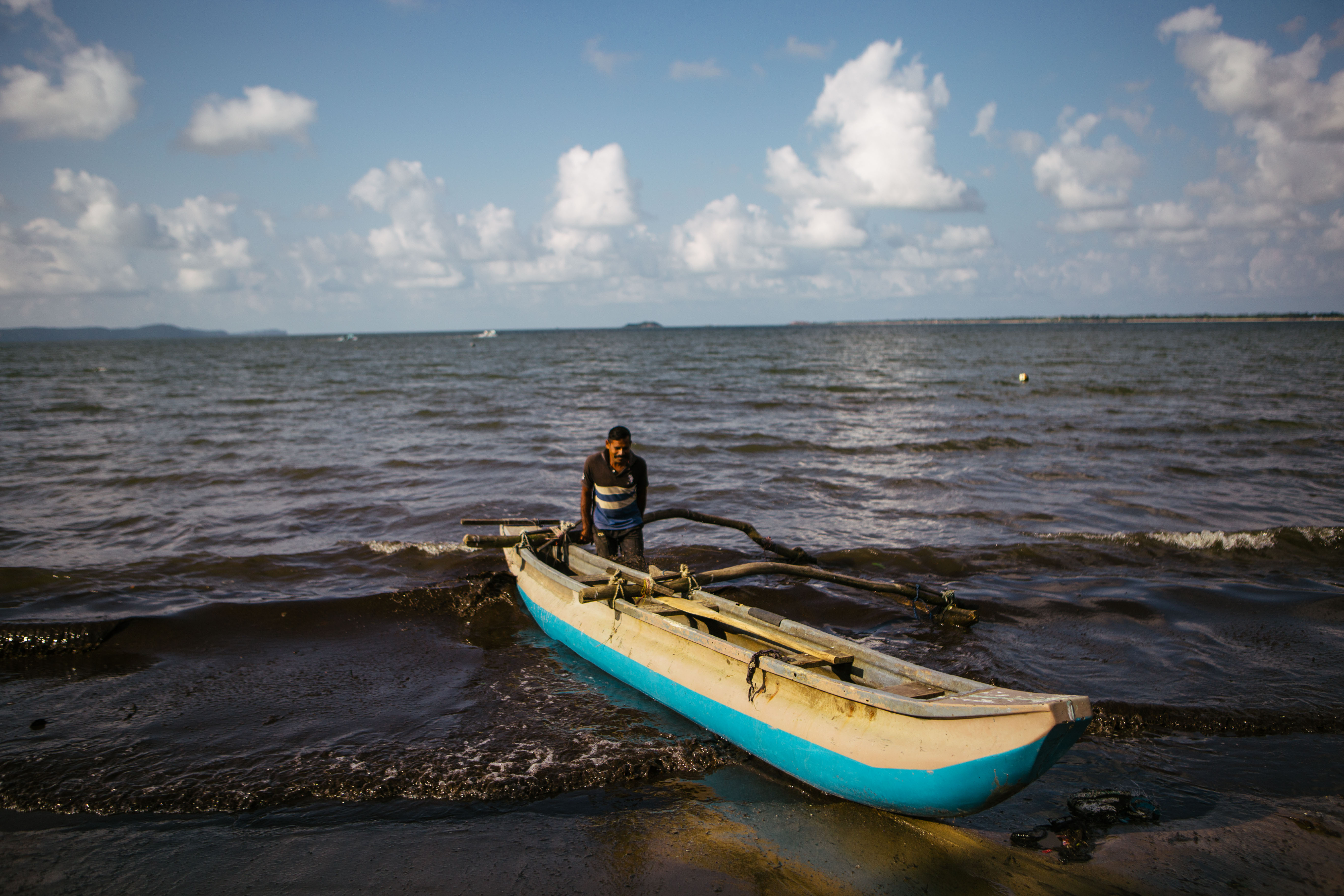 A fisherman pushes his boat to shore at the Ullackalie lagoon fish landing site on the east coast of Sri Lanka. Fishermen only take small amounts of water with them and can become dangerously dehydrated in the long hours at sea