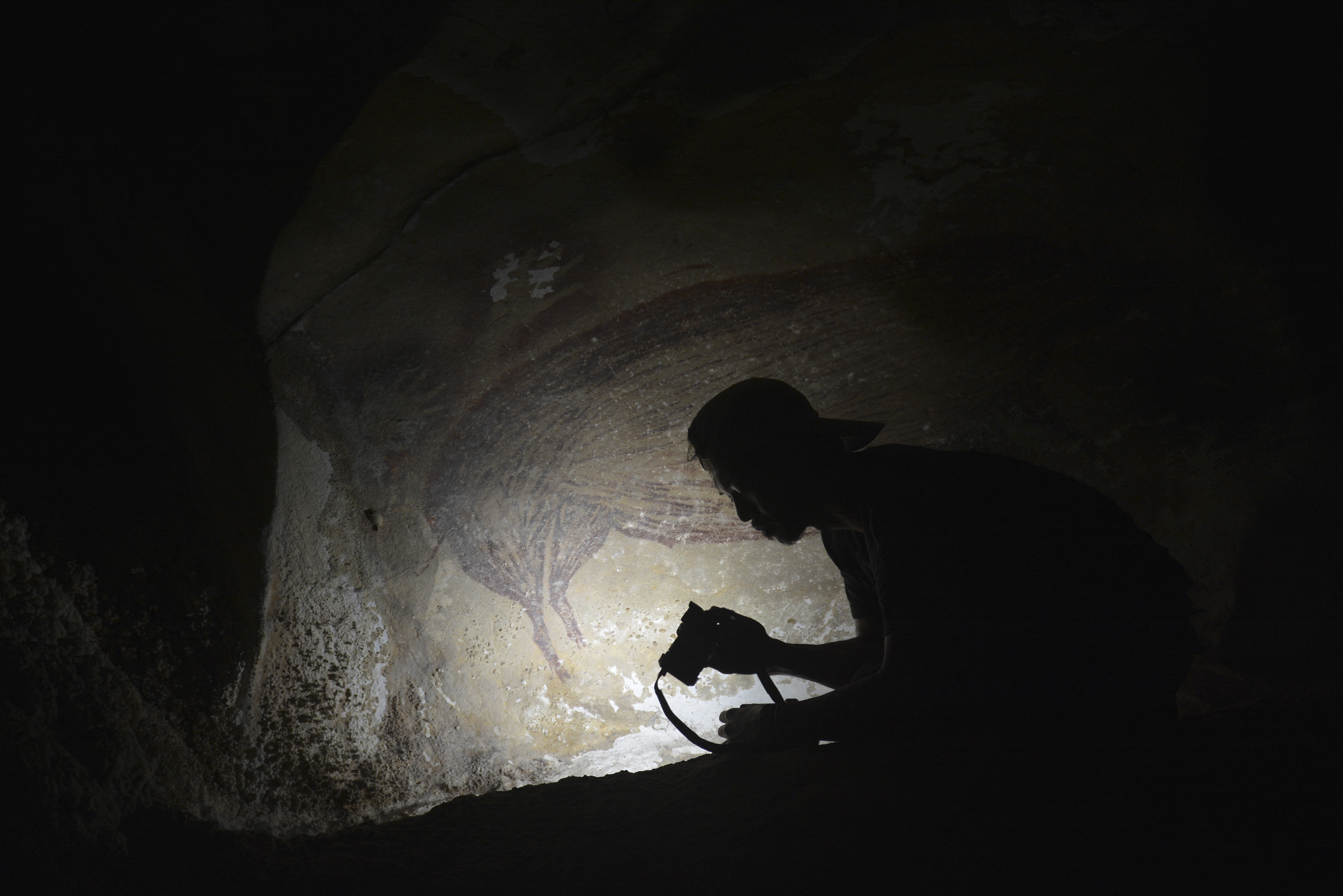 a person holds a camera in a dark cave