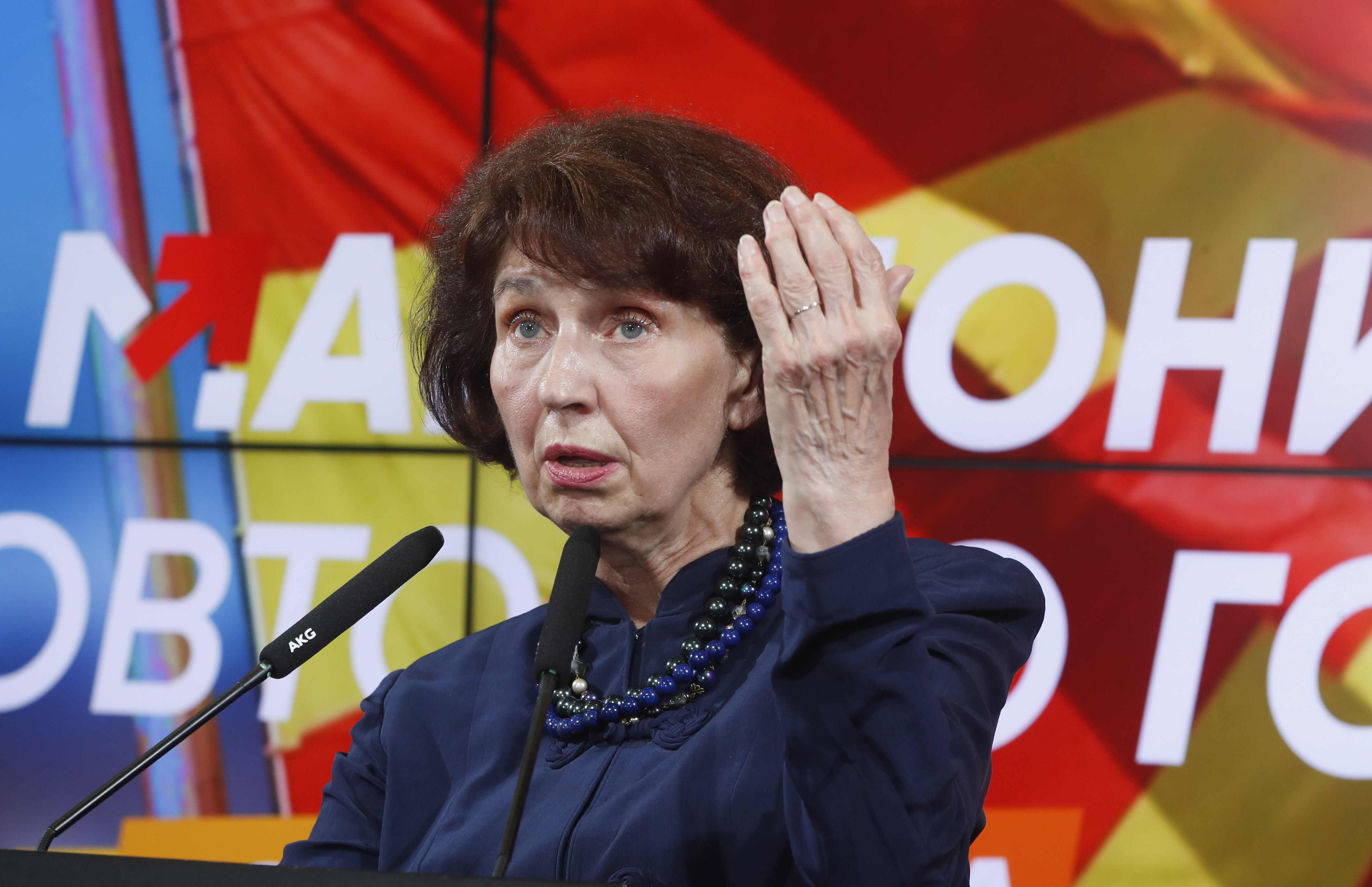 Gordana Siljanovska Davkova speaks into a microphone as she celebrates her election win, one hand raised in gesture.