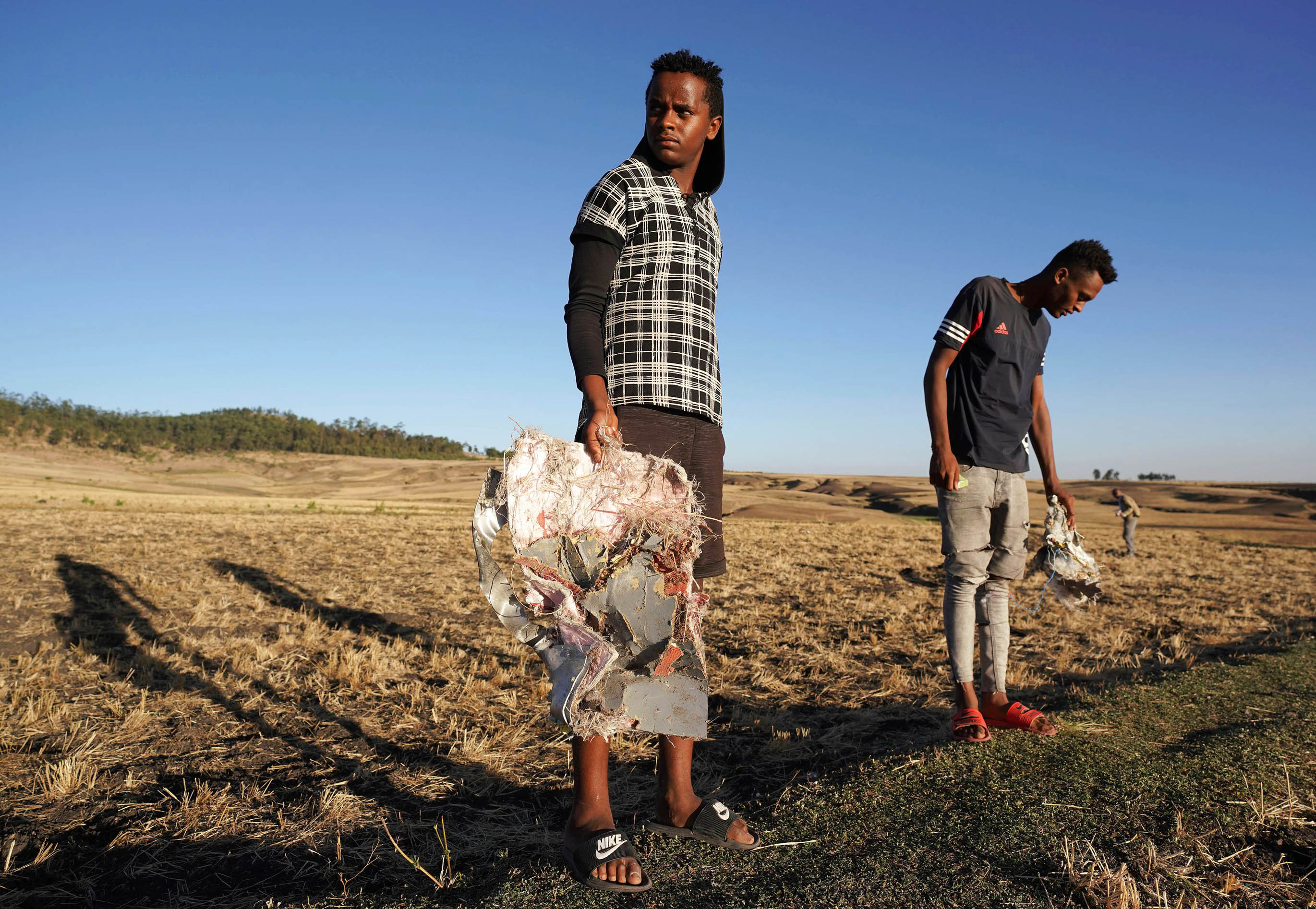Residents collect debris at the scene where Ethiopian Airlines Flight 302 crashed in a wheat field just outside the town of Bishoftu, 62km southeast of Addis Ababa on March 10, 2019
