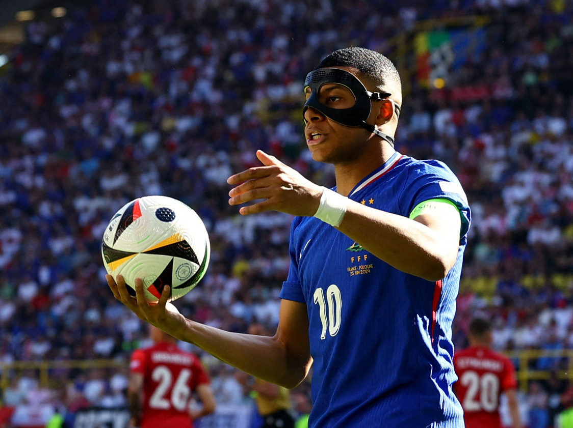 Football player wearing protective nose mask throws the ball into play during a match.