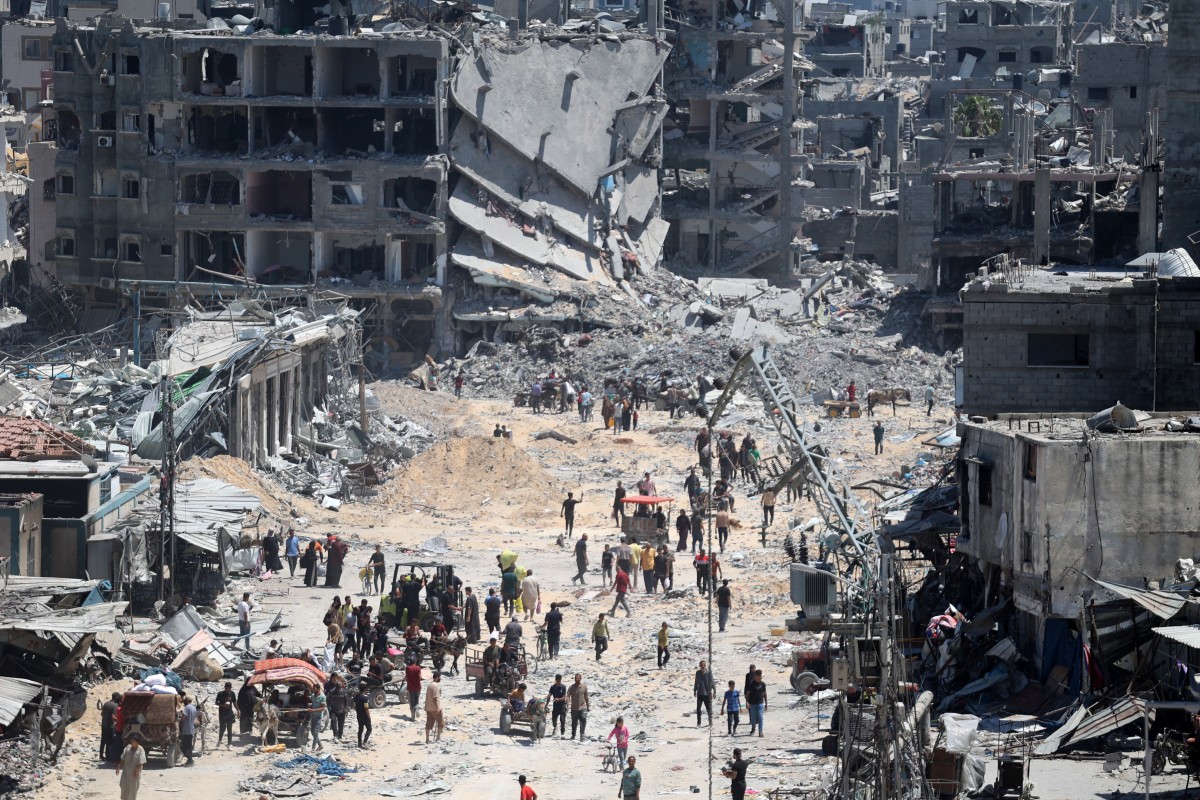 Palestinians carry some salvaged belongings as they leave the Jabalia
