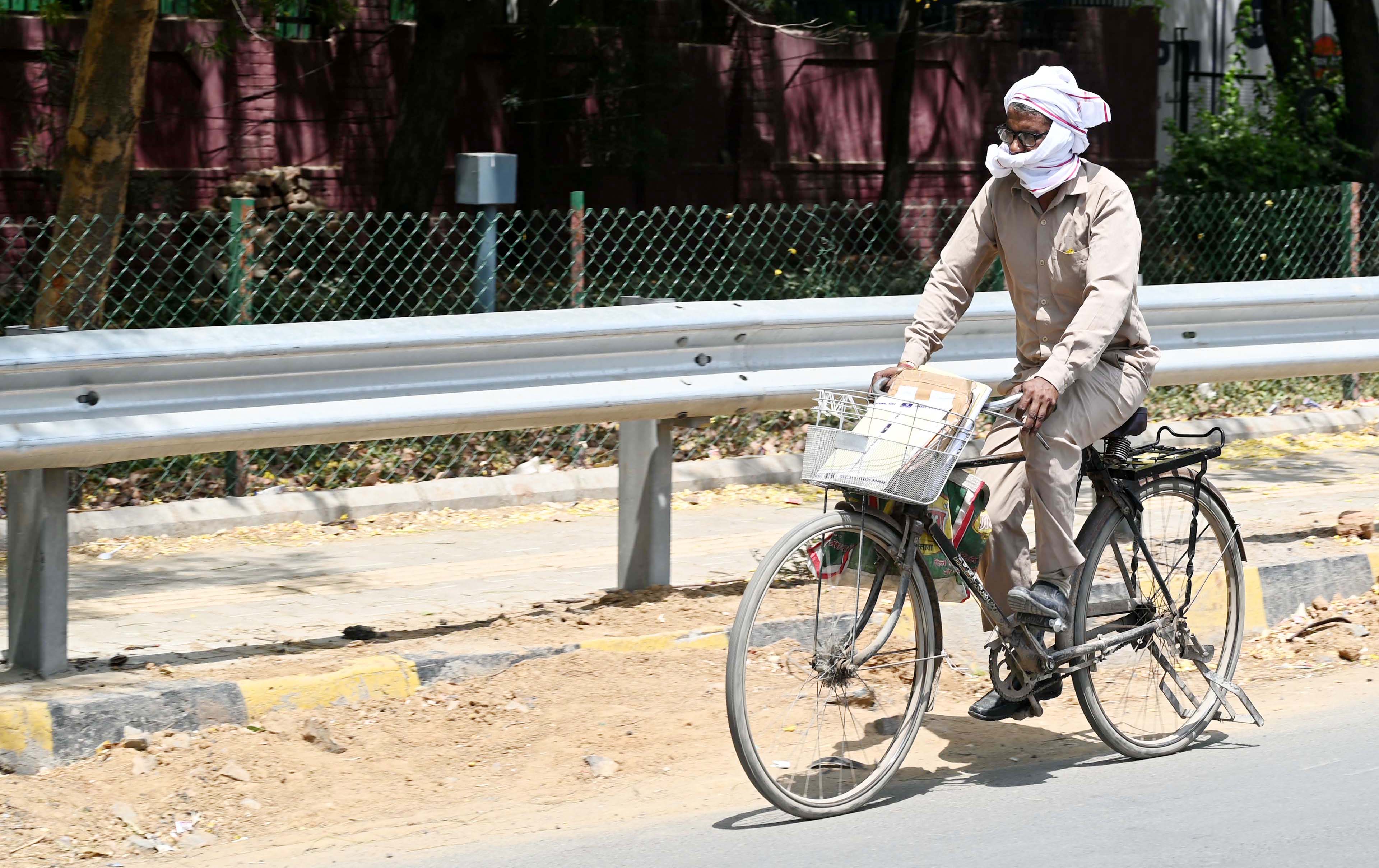 GURUGRAM, INDIA - MAY 20: A postman going to deliver the letter in heat wave on a hot summer day at sector-17/18 dividing road near Iffco chowk on May 20, 2024 in Gurugram, India. The India Meteorological Department (IMD) weather forecast report states that heatwave to severe heatwave conditions is expected in Punjab, Haryana, and Delhi until May 23, in Rajasthan over the next three days, and in Uttar Pradesh until May 21. (Photo by Parveen Kumar/Hindustan Times via Getty Images)