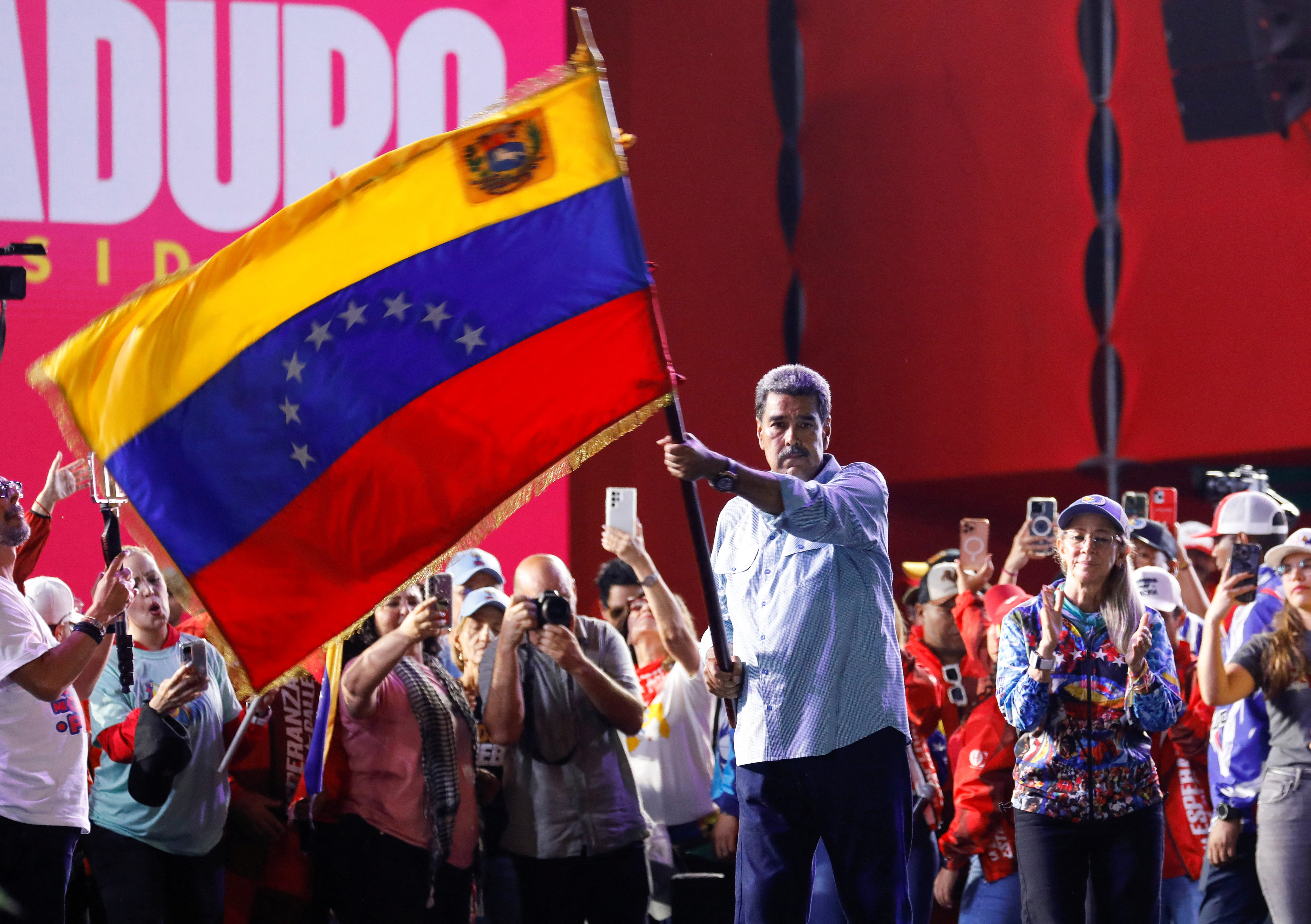Venezuelan President Maduro, who is seeking re-election for a third term, waves Venezuela’s national flag during the closing of his political campaign in Caracas