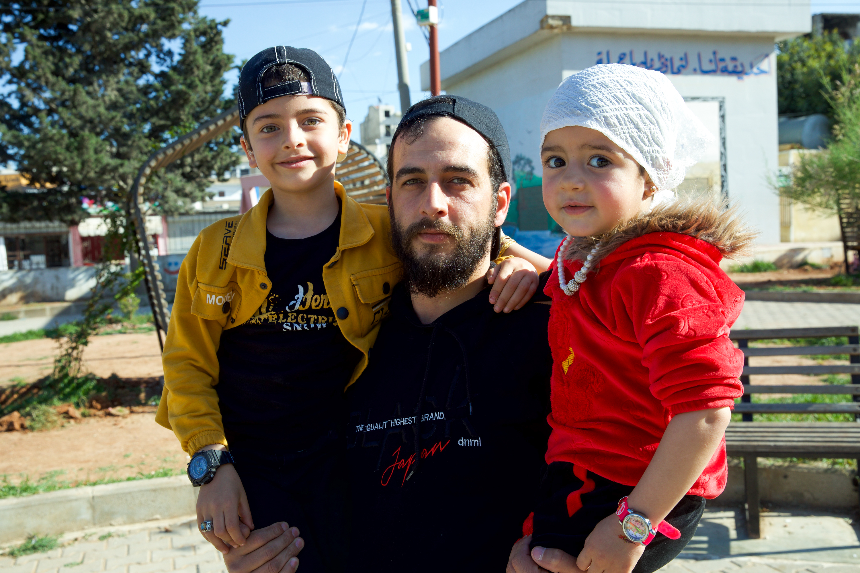 Khalid Abdel Razek Abu al-Zumar holding his son Aslan and daughter Celine in a park in Idlib in April