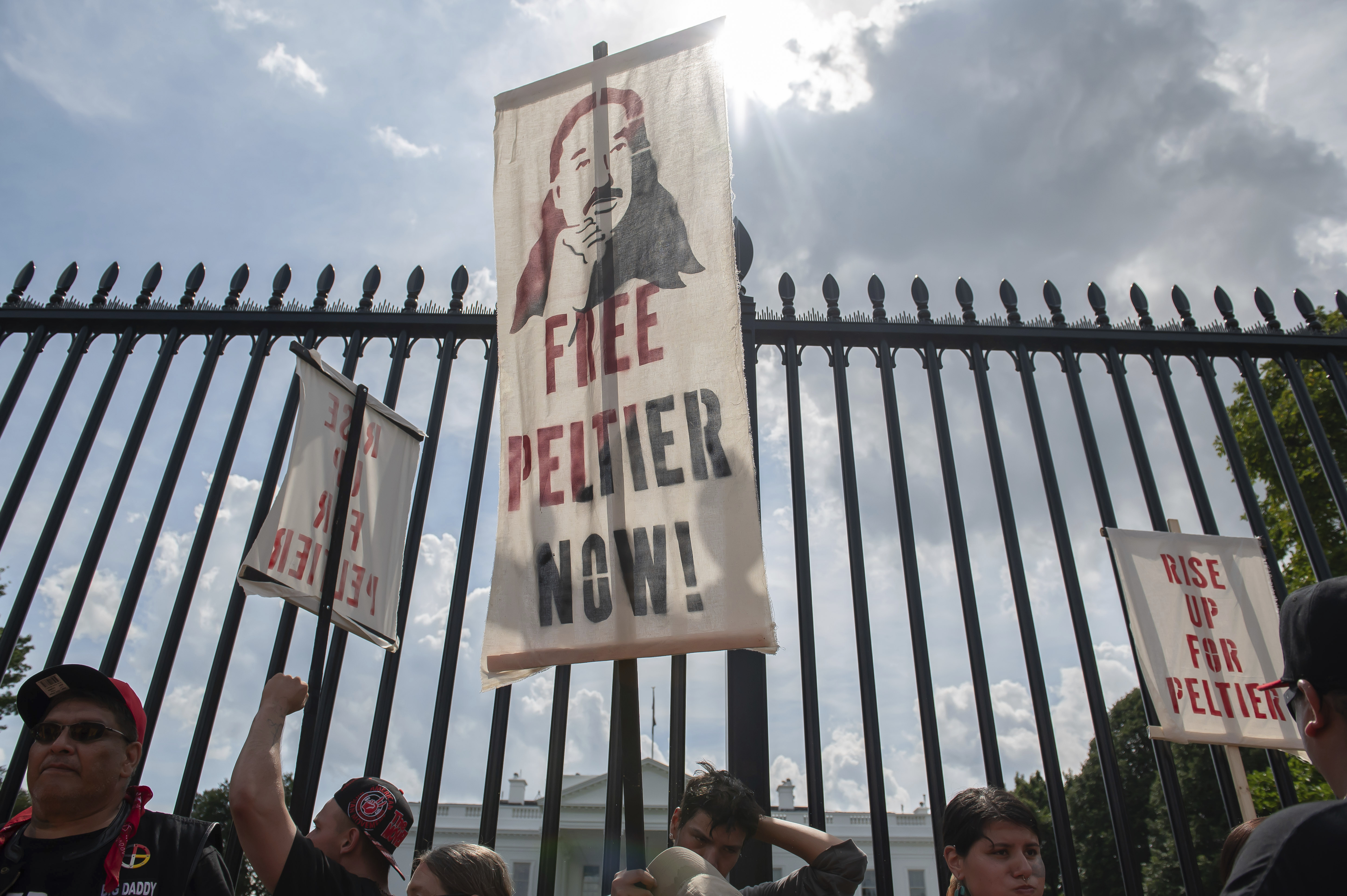 An advocate lifts a picket sign that reads "Free Peltier now."