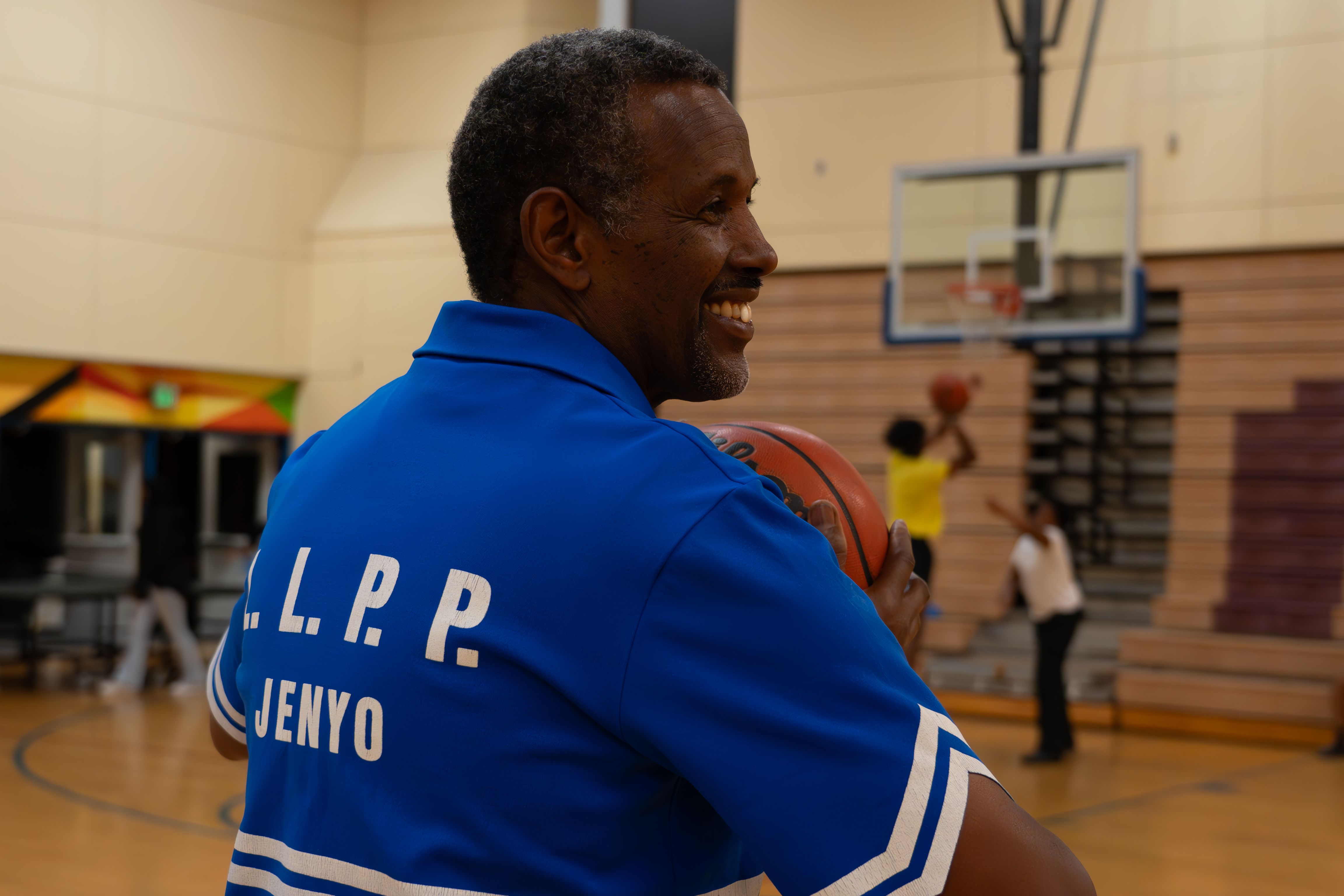 Abdiaziz Guled, wearing his former national team jersey, joins in with the basketball in the gym of Ashland Middle School at this year’s reunion