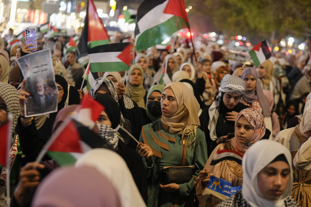 people march at night with Palestinian flags