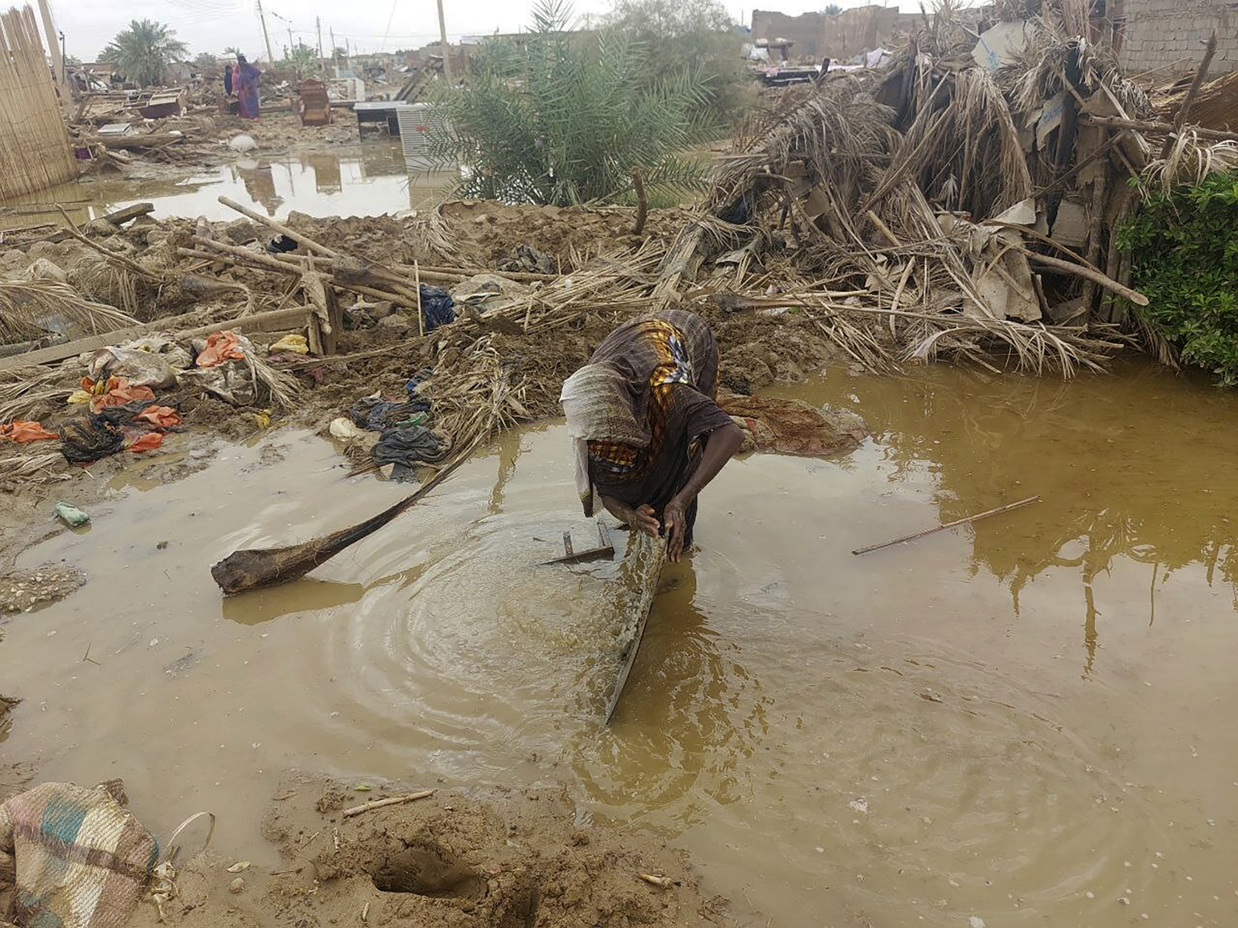 A woman sorts through floodwaters near her damaged home near the city of Abu Hamdan in Northern Sudan