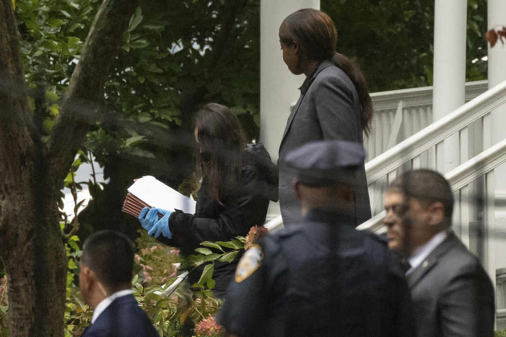 A person wearing gloves carries documents