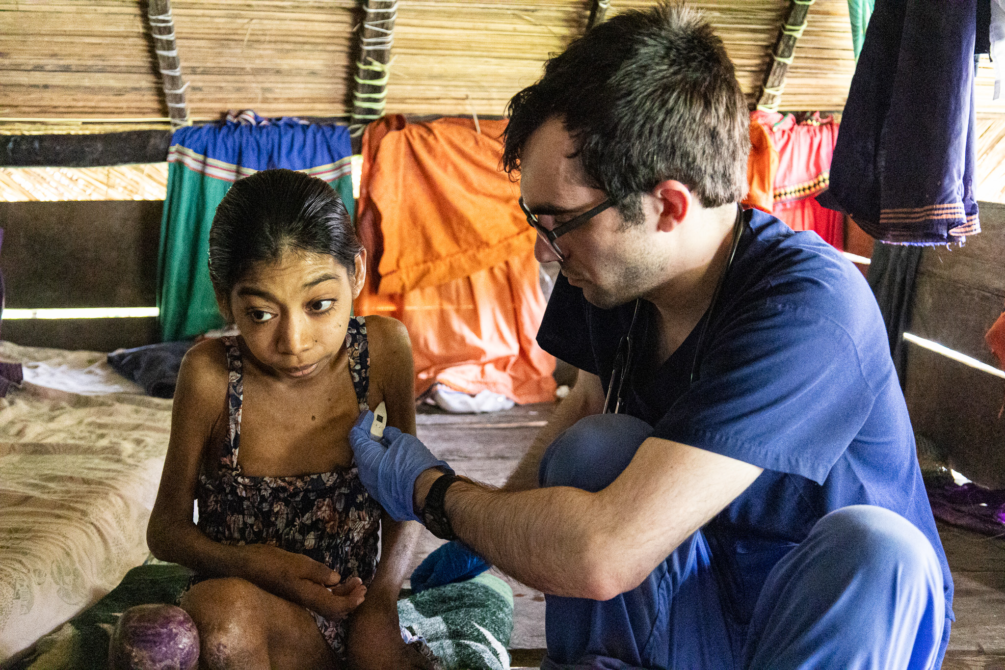 Floating Doctors volunteer Devin Herald takes the temperature of Omayra Abrego, a 25-year-old Ngabe-Bugle woman thought to have juvenile idiopathic arthritis, at her home in the village of Wari, Panama