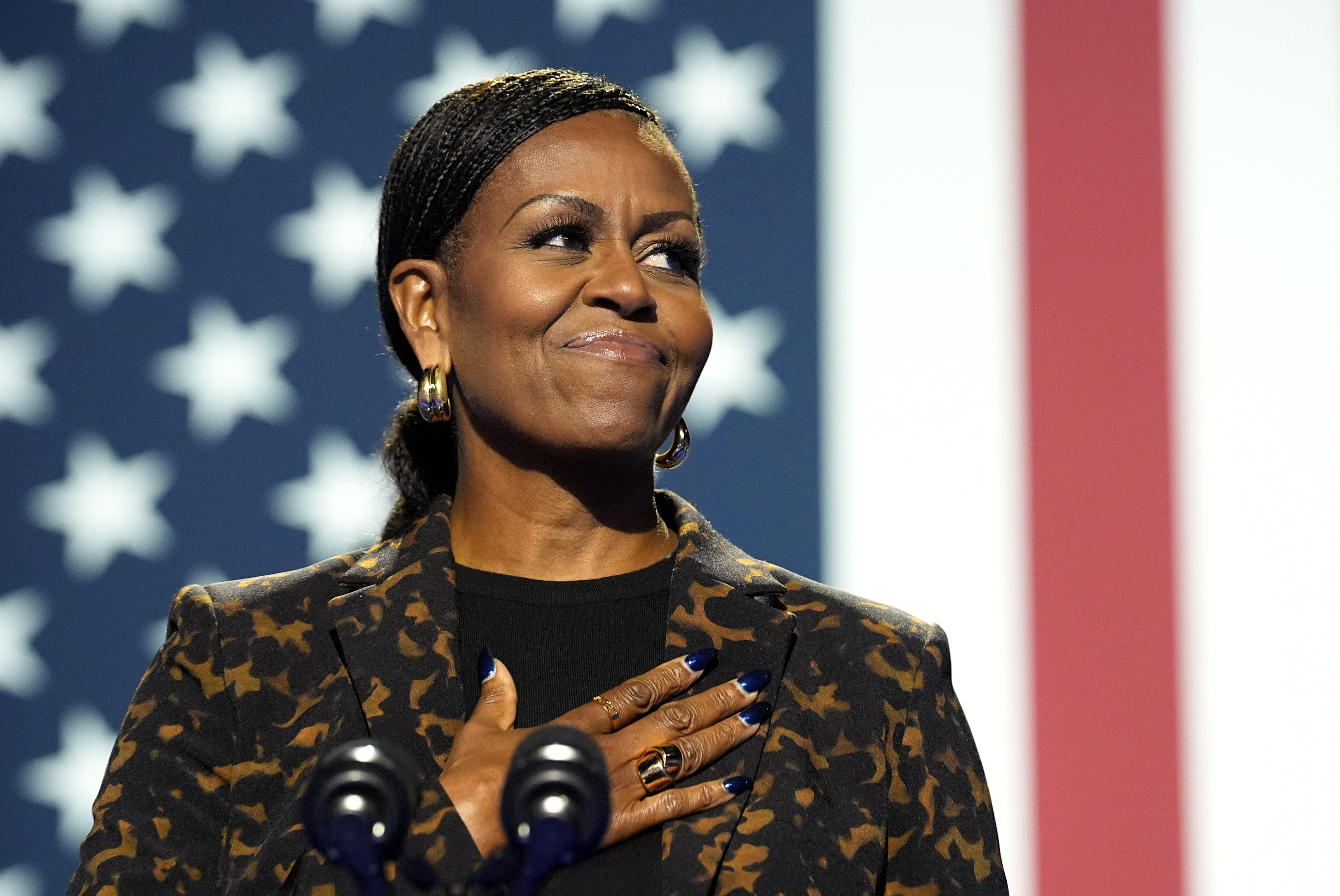 Michelle Obama in front of a US flag, with hand on heart