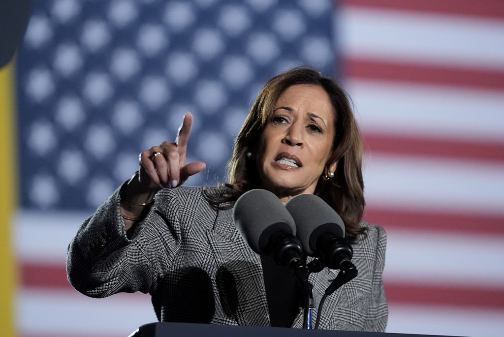 a woman speaks in front of a US flag