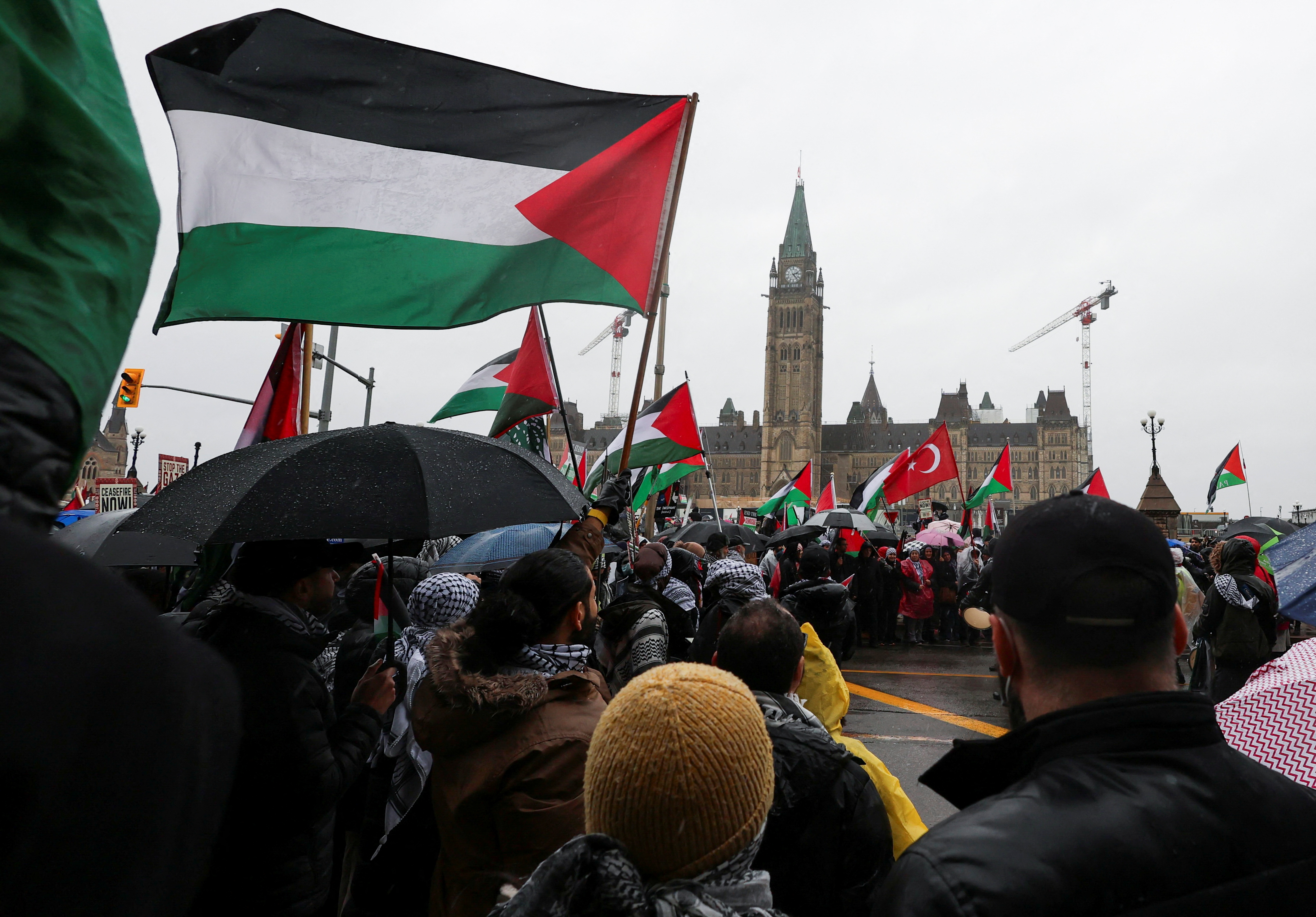 Protesters hold Palestinian flags during a rally in front of the Canadian parliament in Ottawa