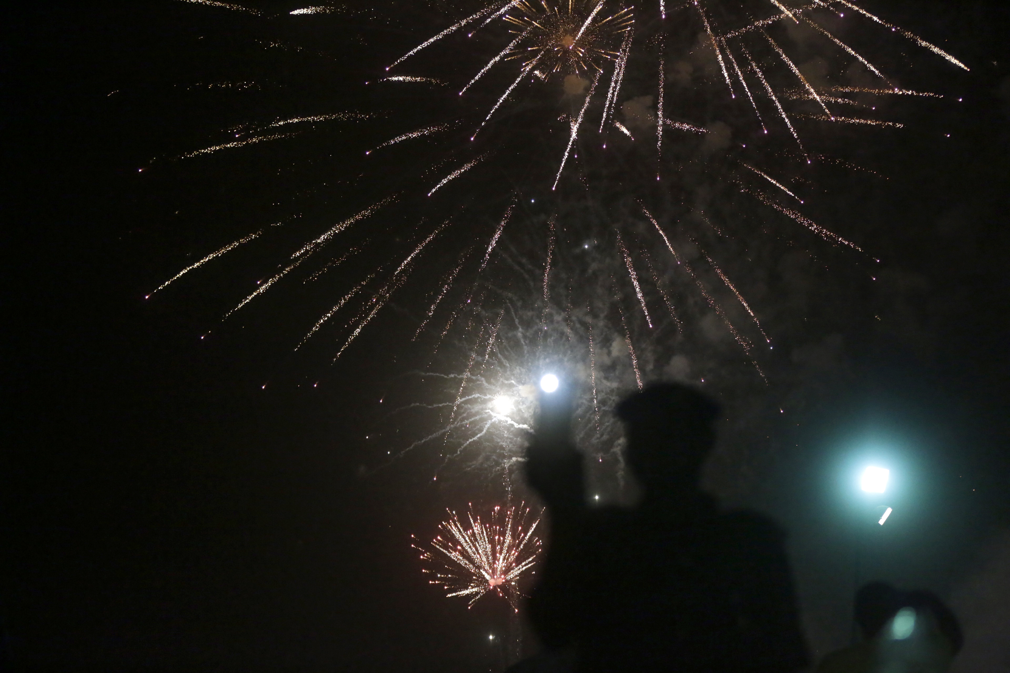 A man records fireworks with his phone to celebrate the New Year in Lagos