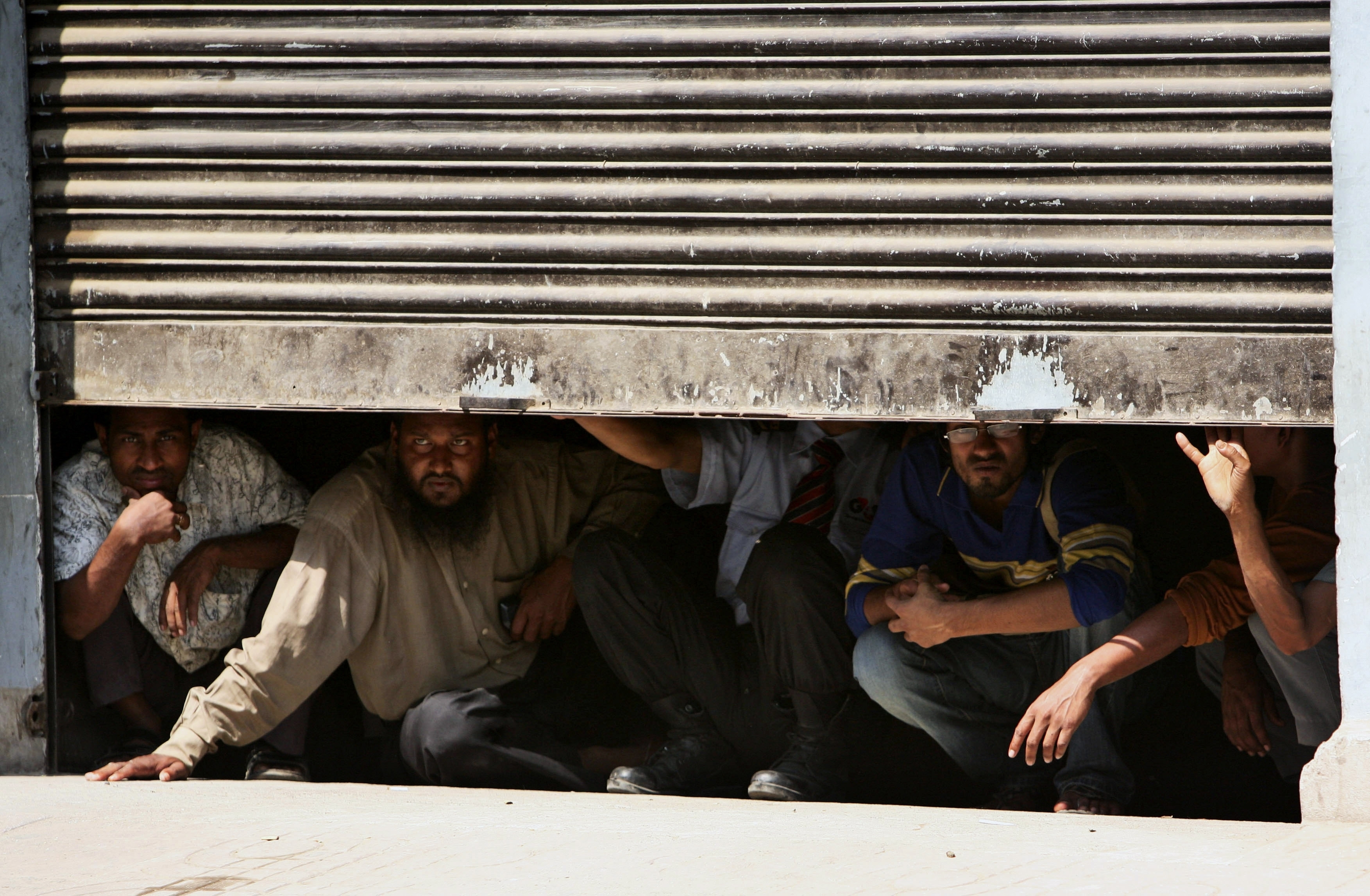 Bangladeshi civilians take shelter in a garage amid firing near the headquarters of Bangladesh Rifles in Dhaka on February 25, 2009