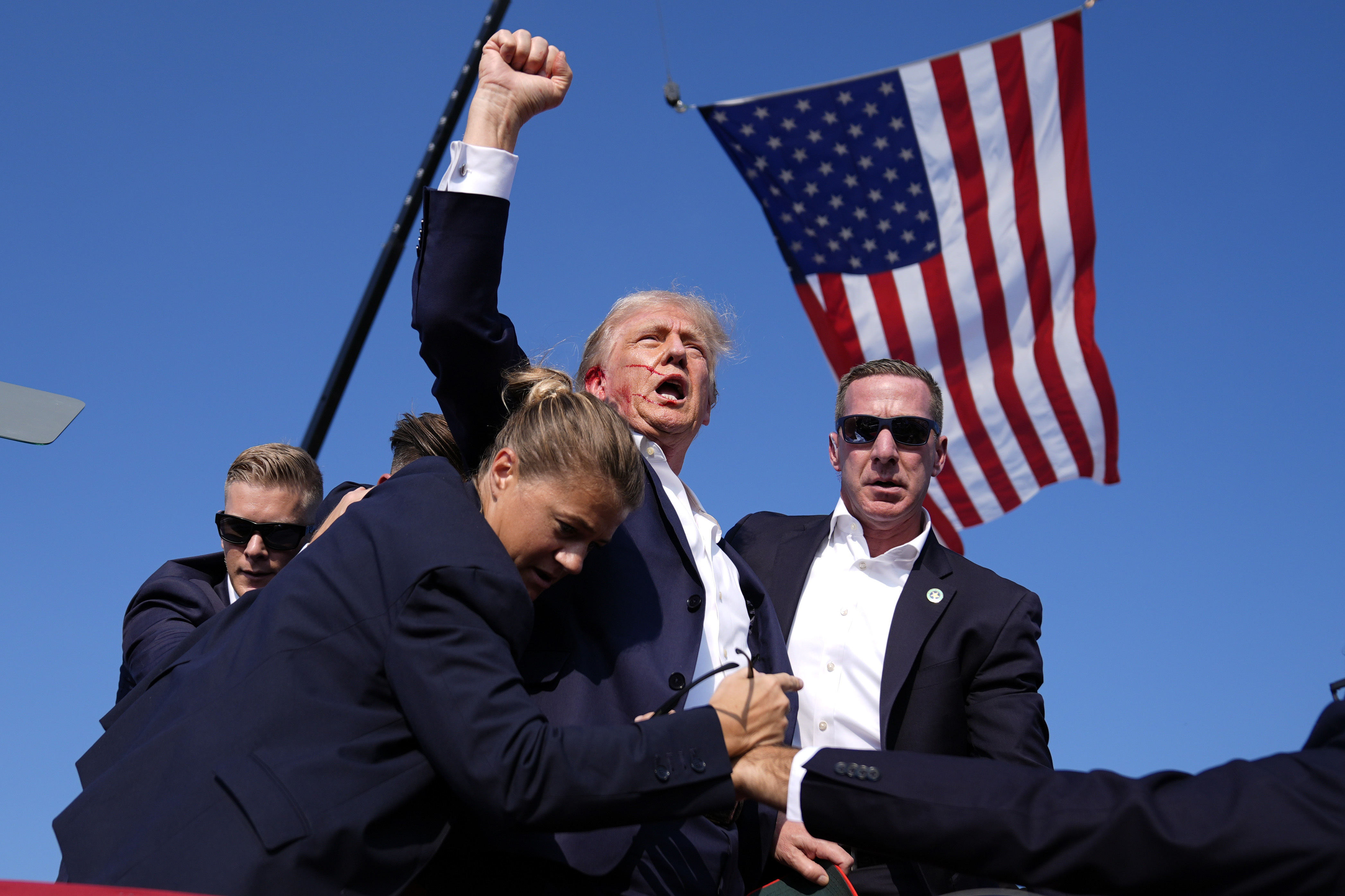 Donald Trump is surrounded by US Secret Service agents after an assassination attempt.