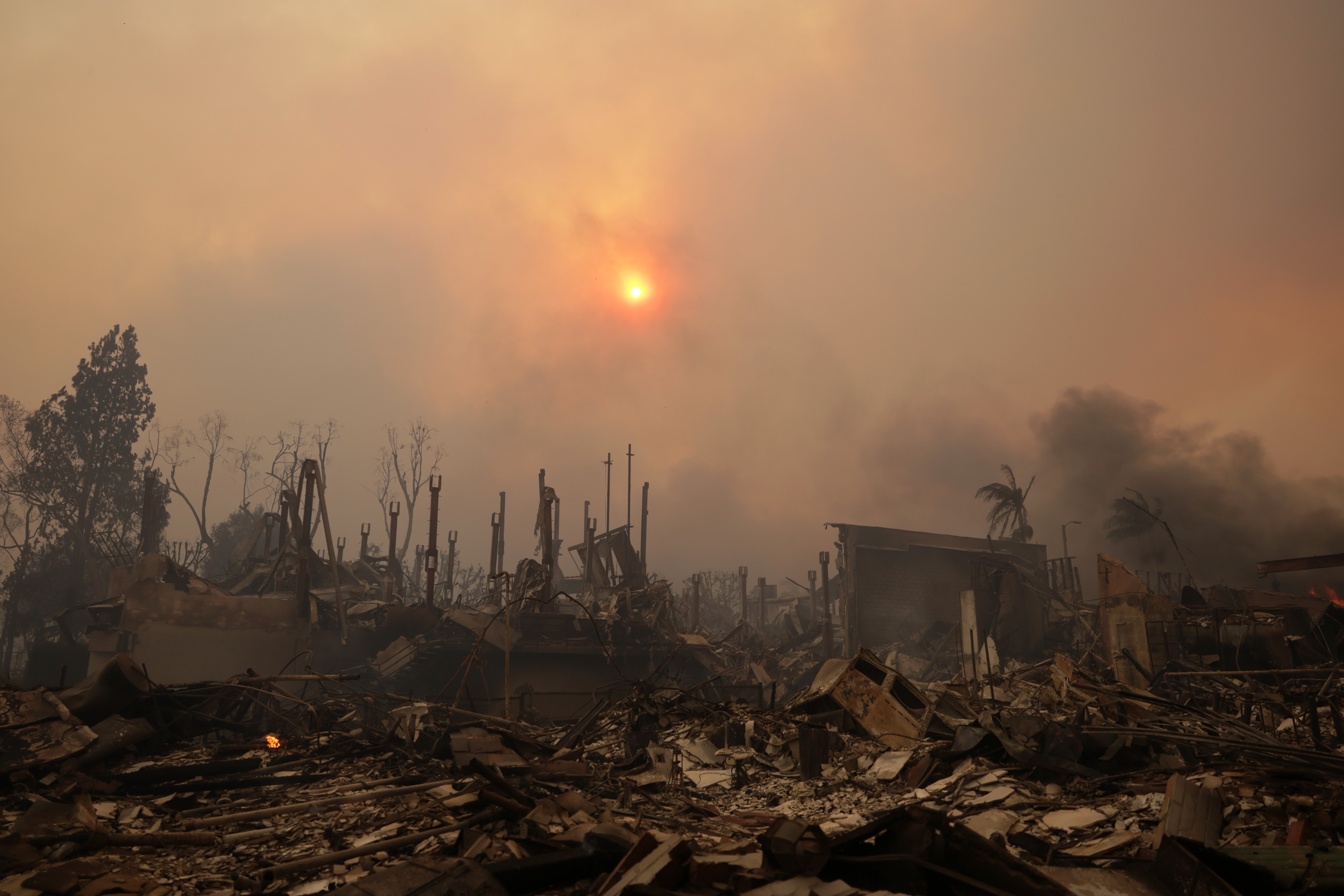 The sun shines through smoke above ruins of homes from the Palisades wildfire in the Pacific Palisades neighborhood of Los Angeles, California, USA, 08 January 2025