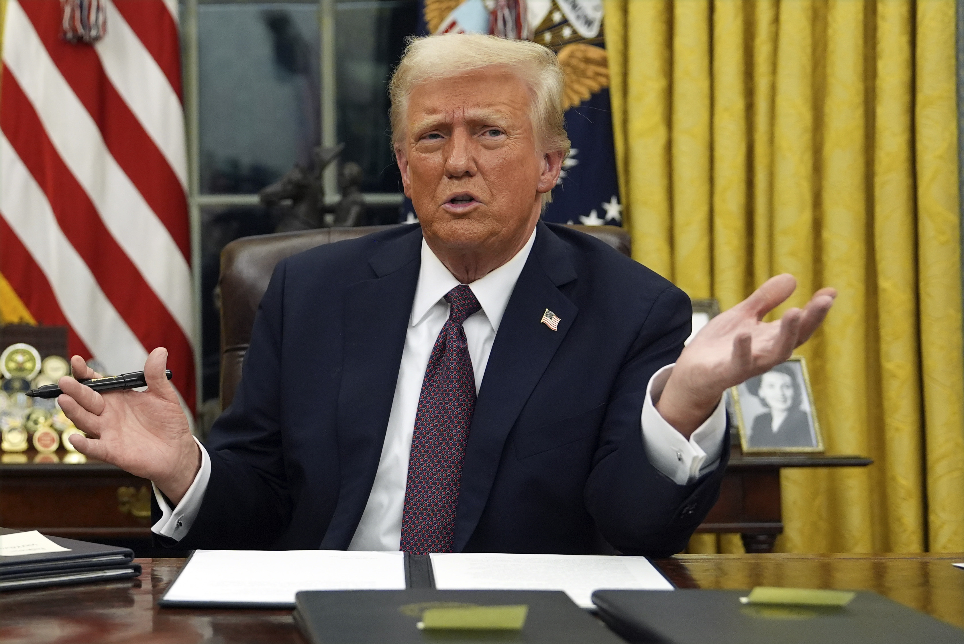 President Donald Trump talks to reporters as he signs executive orders.