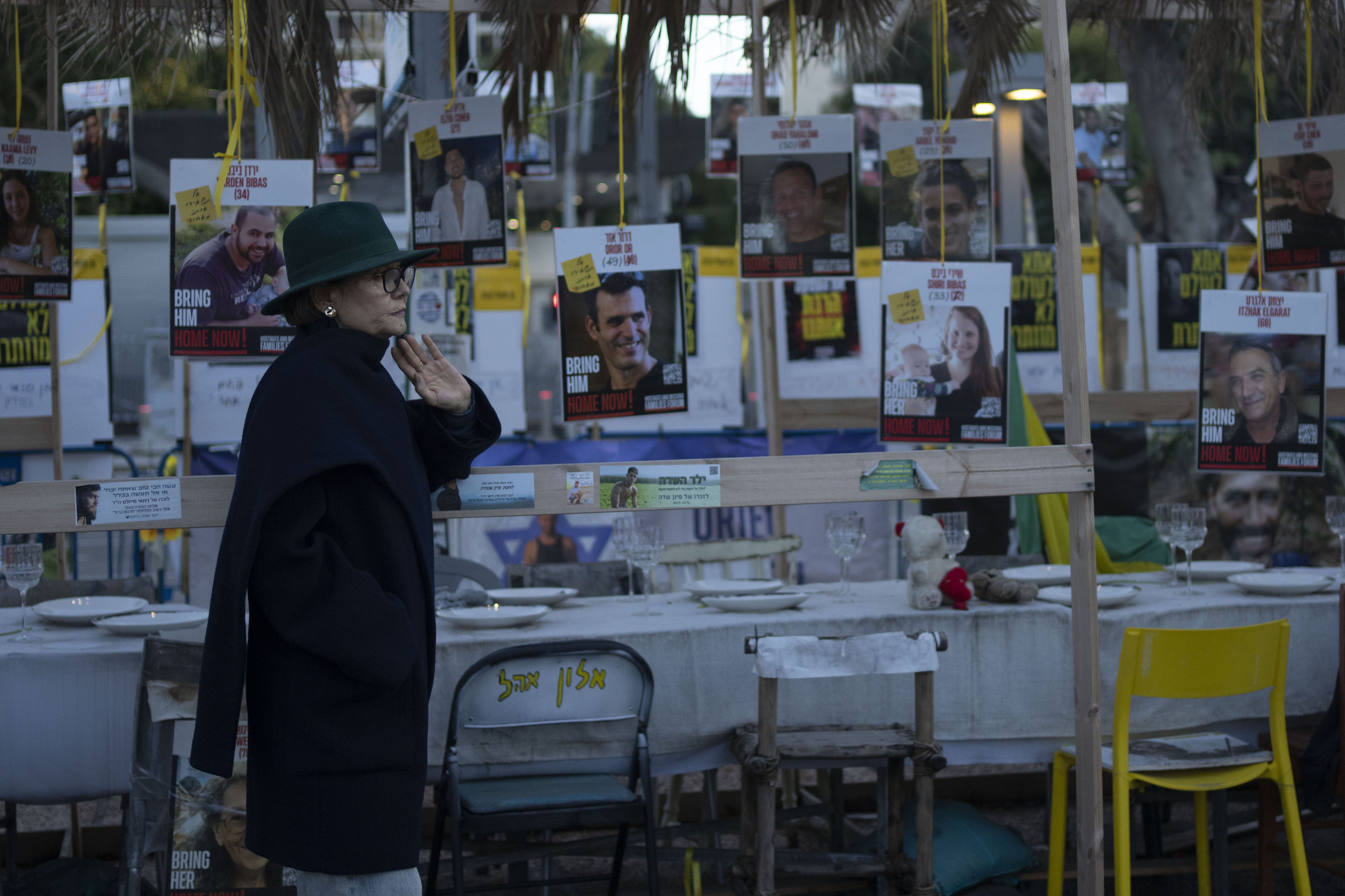 A woman looks at a display of empty chairs representing hostages