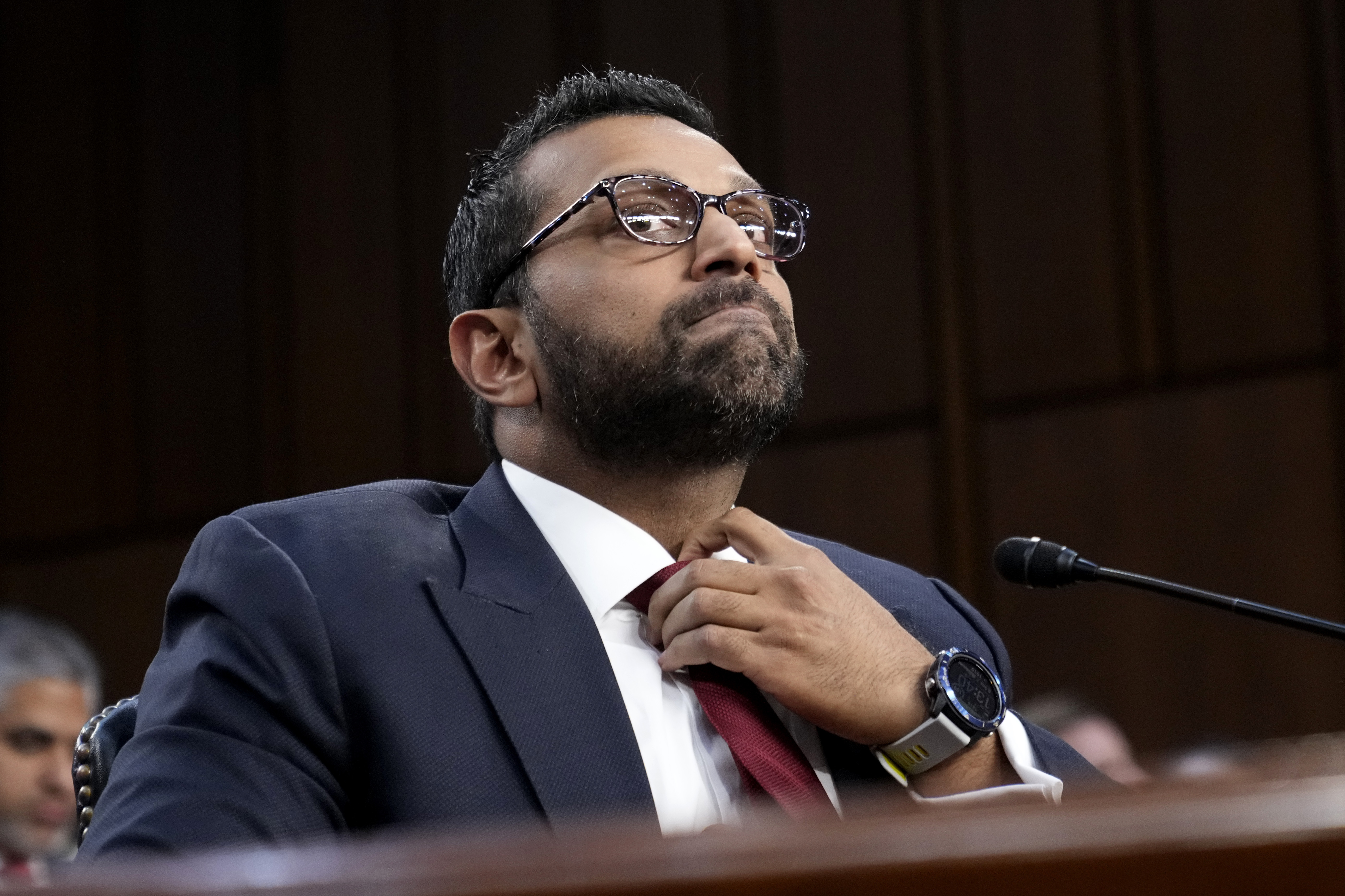 Kash Patel straightens his tie.