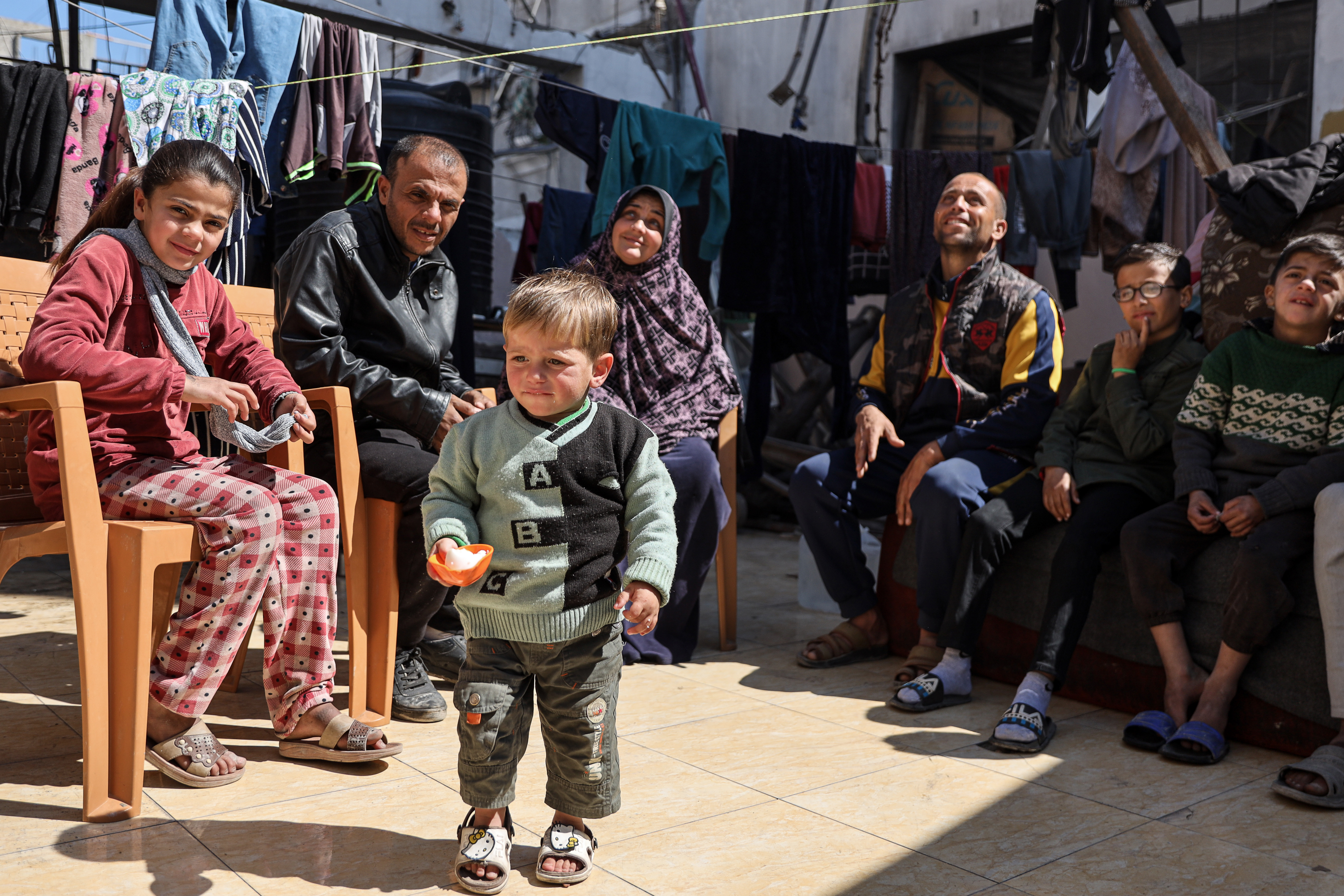 Mohammed (Hamoud) plays happily, watched by his two families