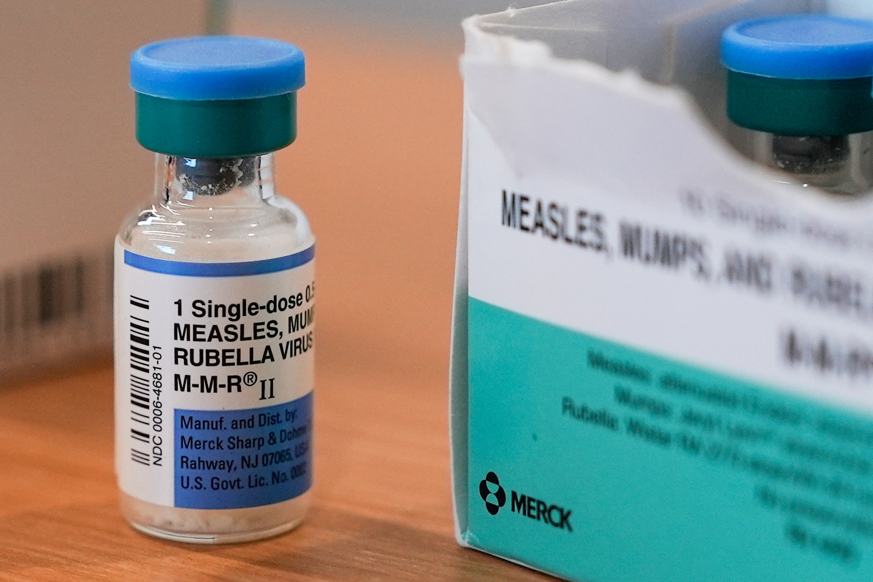 A vial of the measles, mumps and rubella vaccine sits next to its carton on a table.