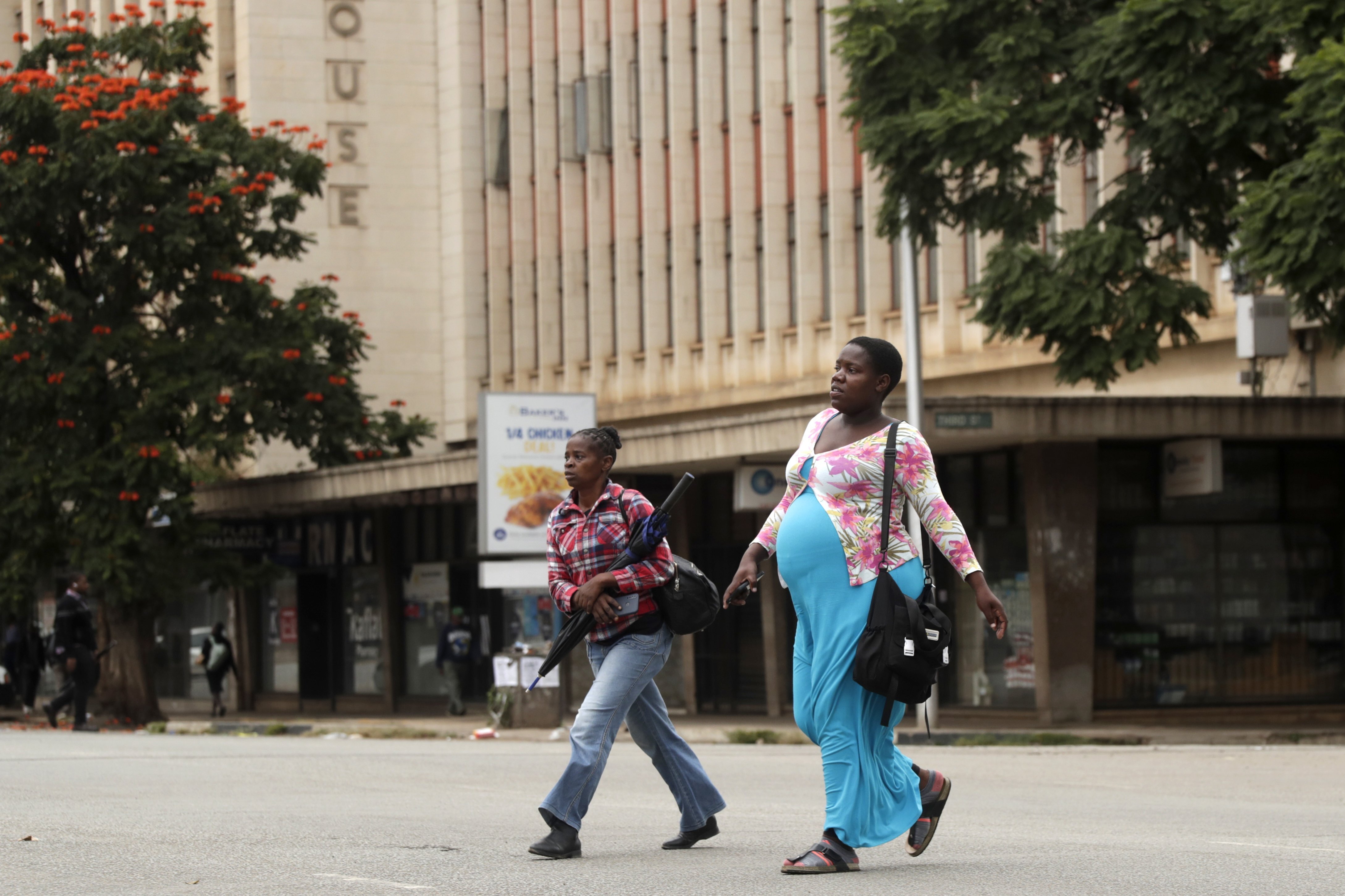 Women walk across a deserted street in downtown Harare, Zimbabwe, on Monday, March 31, 2025, following calls for an antigovernment protest
