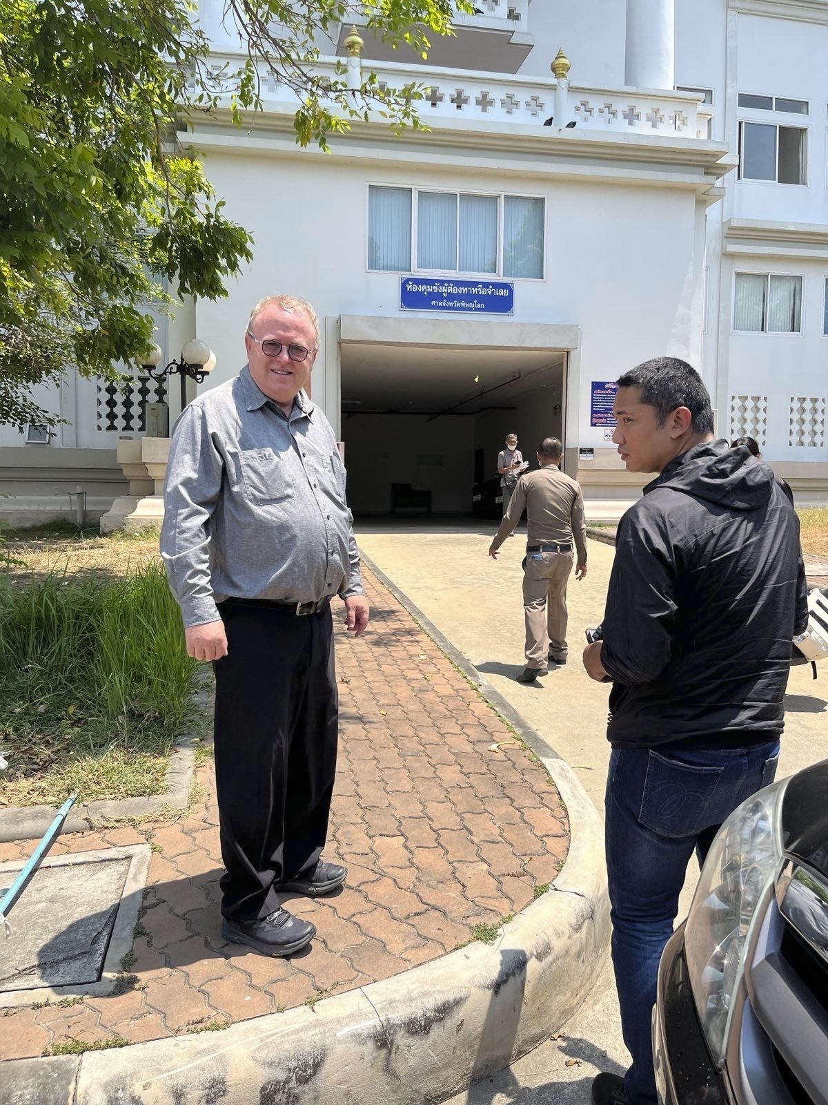 Paul Chambers, left, of Naresuan University, stands outside the police station in Phitsanulok, Thailand, where he was arrested on April 8, 2025, on charges of insulting the monarchy [AP Photo]