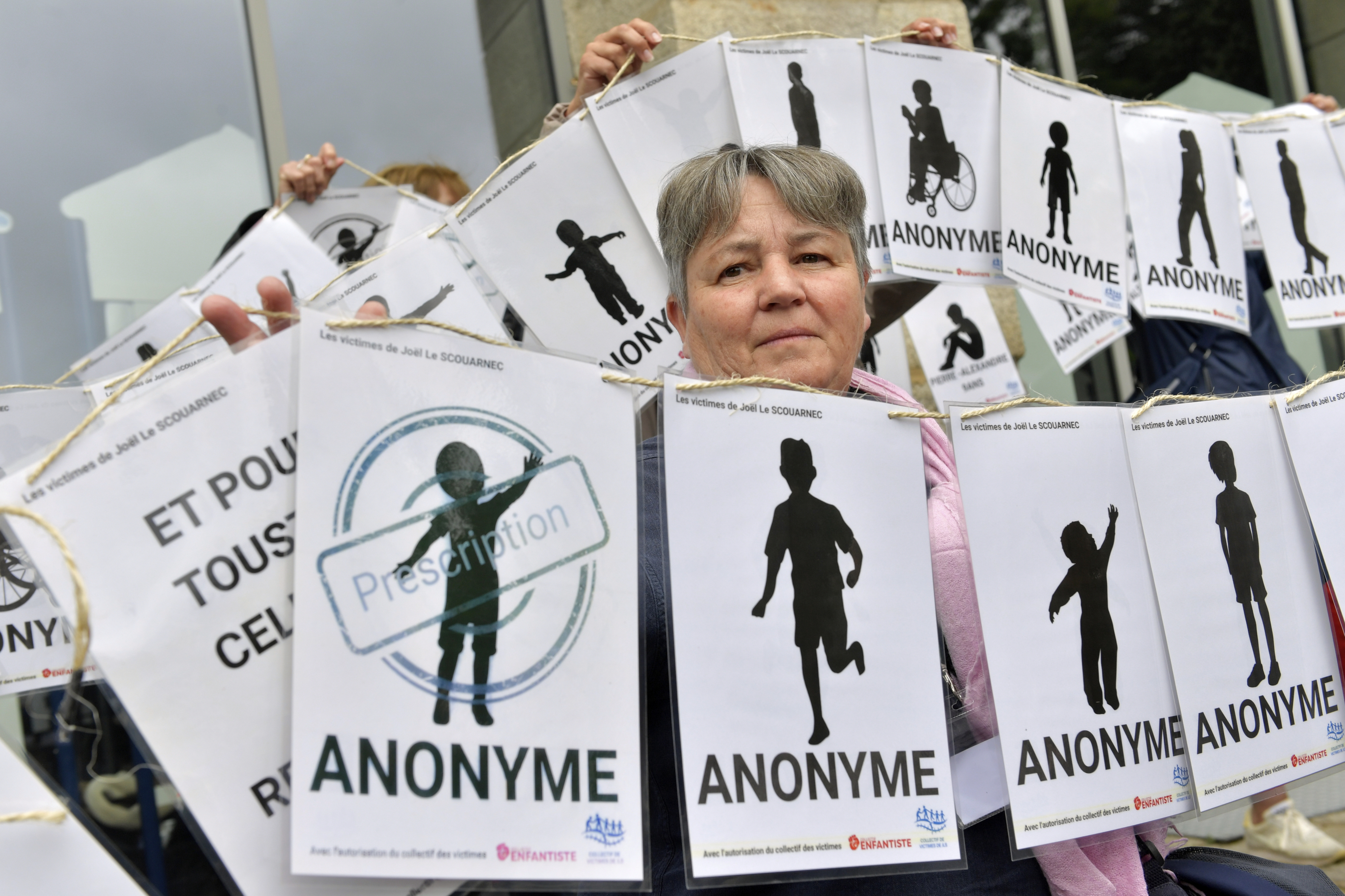 A woman holds a banner representing anonymous victims during a demonstration before Joel Le Scouarnec was convicted in Vannes on May 28, 2025