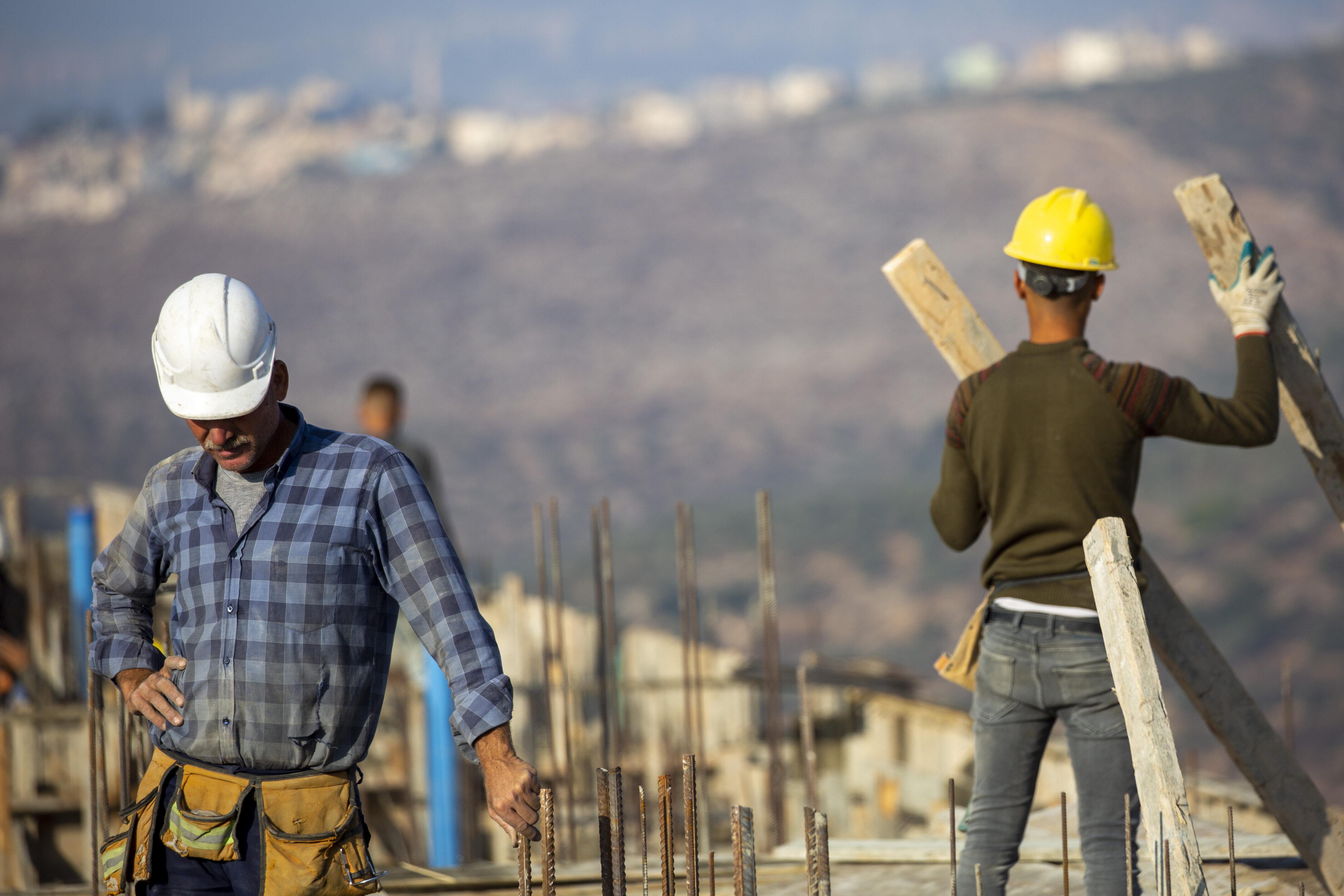 FILE - Palestinian laborers work building new houses in the West Bank Jewish settlement of Bruchin near the Palestinian town of Nablus, Monday, Oct. 25, 2021. After years in Israel’s political wilderness, small dovish parties that support Palestinian statehood and oppose Jewish settlements are back in government. But they are finding their influence is limited, with pro-settler coalition partners showing little appetite for compromise and the country's decades-long occupation churning on. (AP Photo/Ariel Schalit, File)