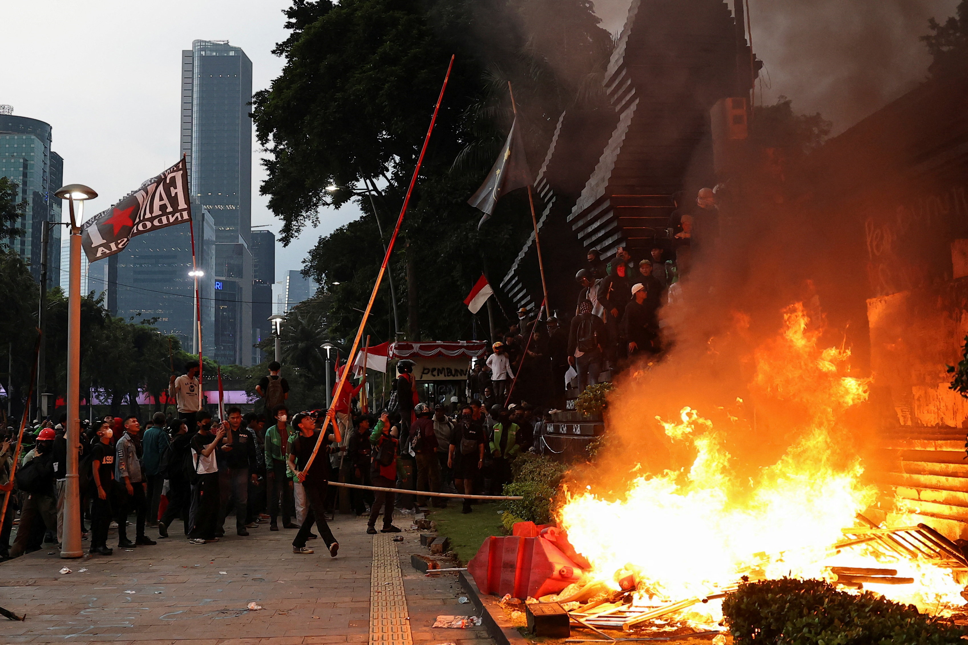 A protester carries a bamboo stick during a protest outside Jakarta police headquarters