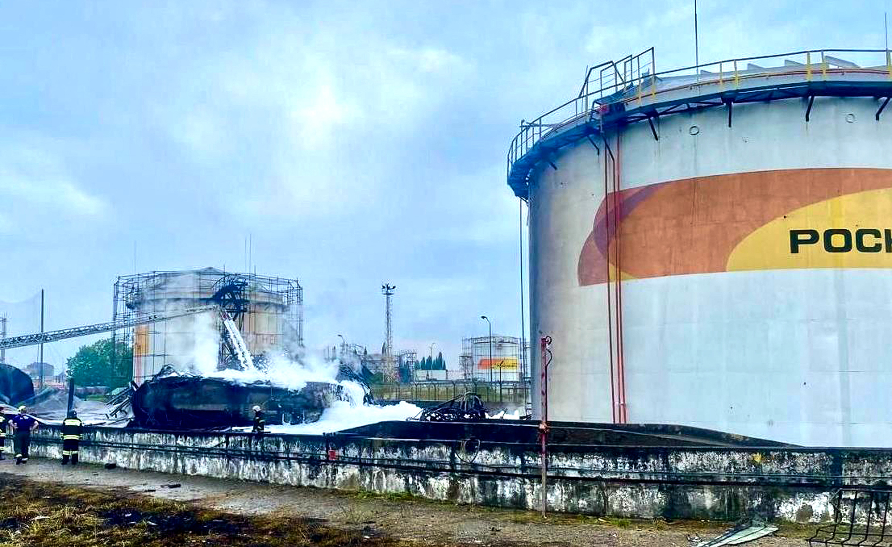 damage can be seen next to a tank at an oil refinery