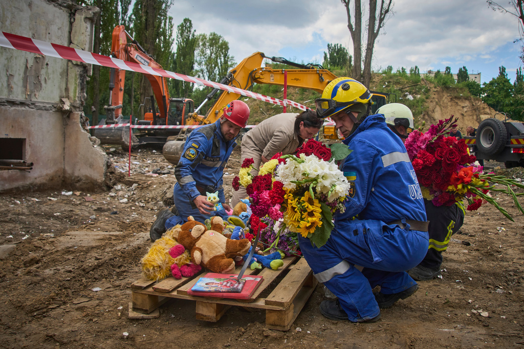 Rescuers lay toys and flowers on the site of Russia’s Thursday night missile strike, which hit a multistorey residential building, killing 31 civilians, including five children, in Kyiv, Ukraine, on Friday