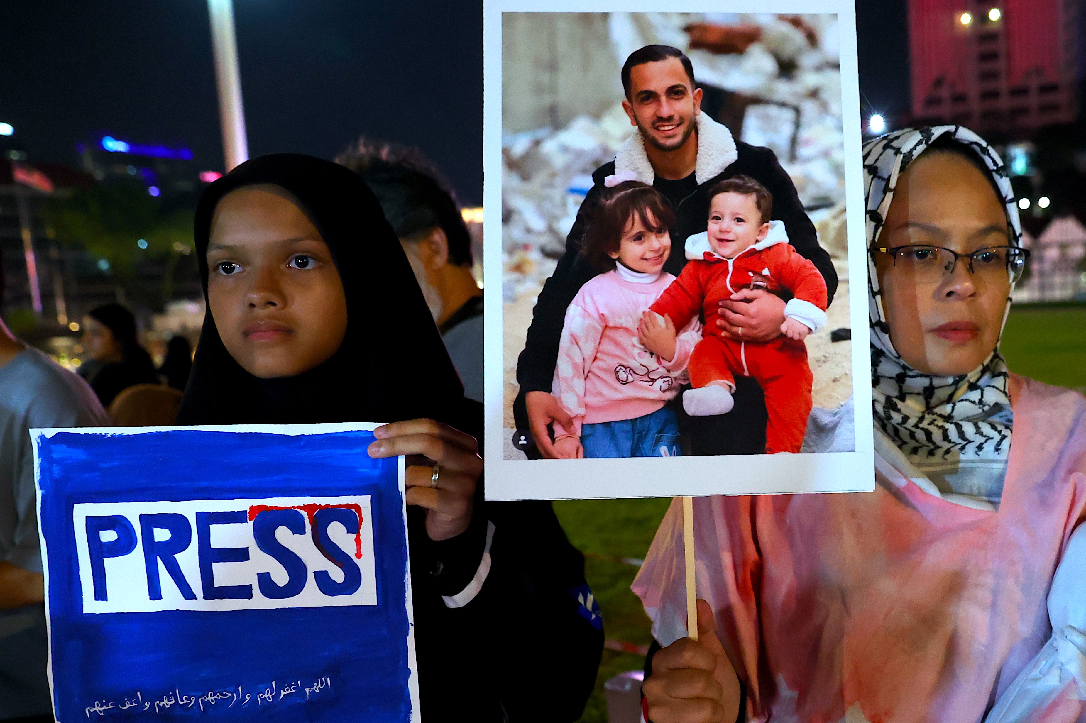 epa12304749 A woman (R) holds the picture of Al Jazeera journalist Anas Al-Shariff and his children during the 'Night of Remembrance for Al Jazeera journalist, Anas Al-Shariff and all journalist' killed by Israel army in Gaza, in Kuala Lumpur, Malaysia, 16 August 2025. At least seven people, including five members of the Al Jazeera team, were killed in an Israeli strike on their tent outside Gaza's Al-Shifa Hospital late 10 August 2025. Israel's military claimed direct responsibility for the attack EPA/FAZRY ISMAIL