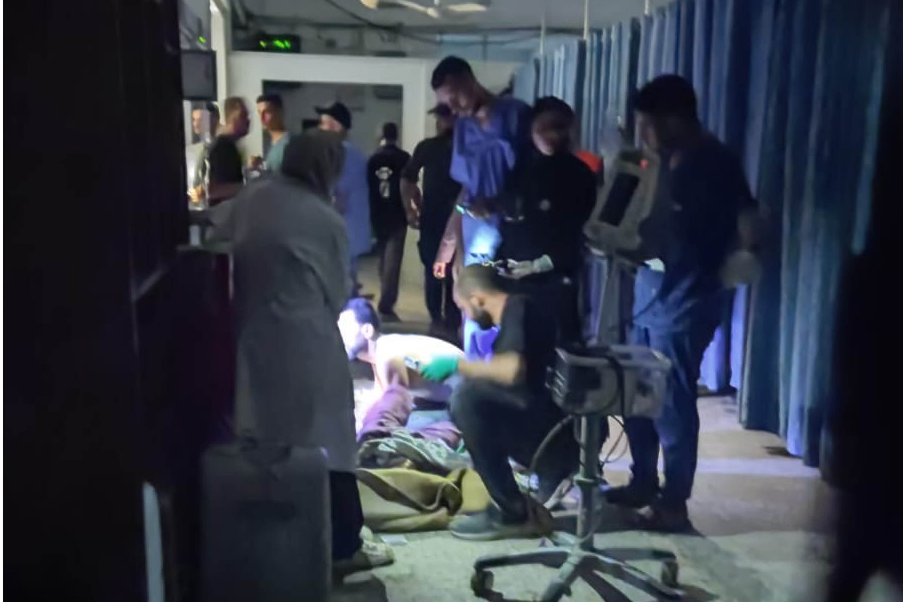 Medical staff at al-Shifa hospital treating a patient under the light of a mobile phone [Courtesy of Hadeel Awad]