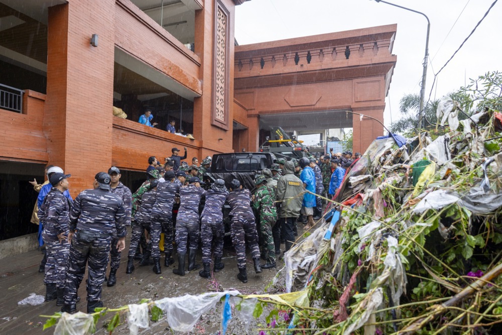 People and military personnel clean up a street after a flood in Denpasar, Bali, Indonesia
