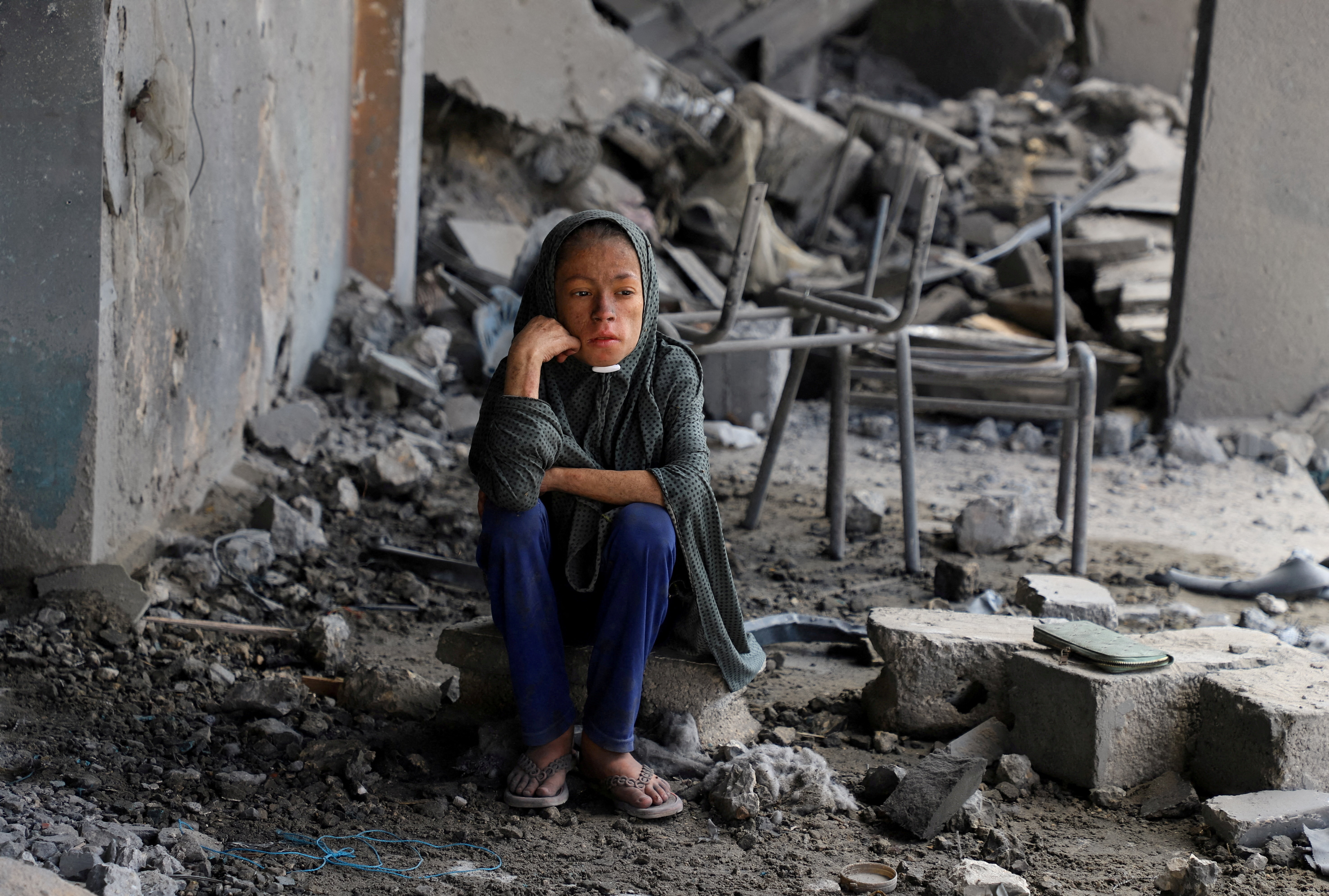 A Palestinian girl sits amid debris at a United Nations school where displaced people were taking shelter, after it was hit in overnight Israeli strikes, amid an Israeli military operation, at Zeitoun neighbourhood in Gaza City