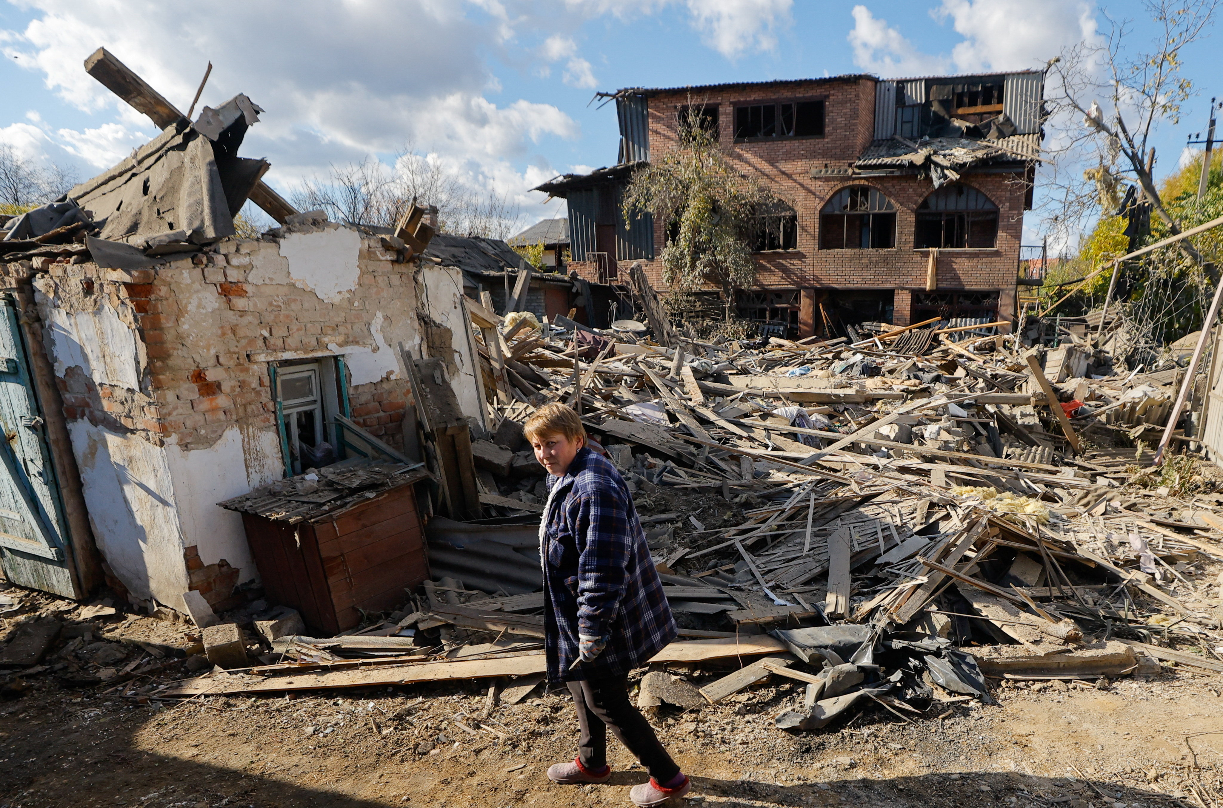 Oksana Lavrenteva, 52, walks past rubble of her house following what Russian-installed authorities described as an overnight Ukrainian missile strike, amid the Russia-Ukraine military conflict in Yasynuvata (Yasinovataya) in the Donetsk region, a Russian-controlled area of Ukraine, October 26, 2025. REUTERS/Alexander Ermochenko