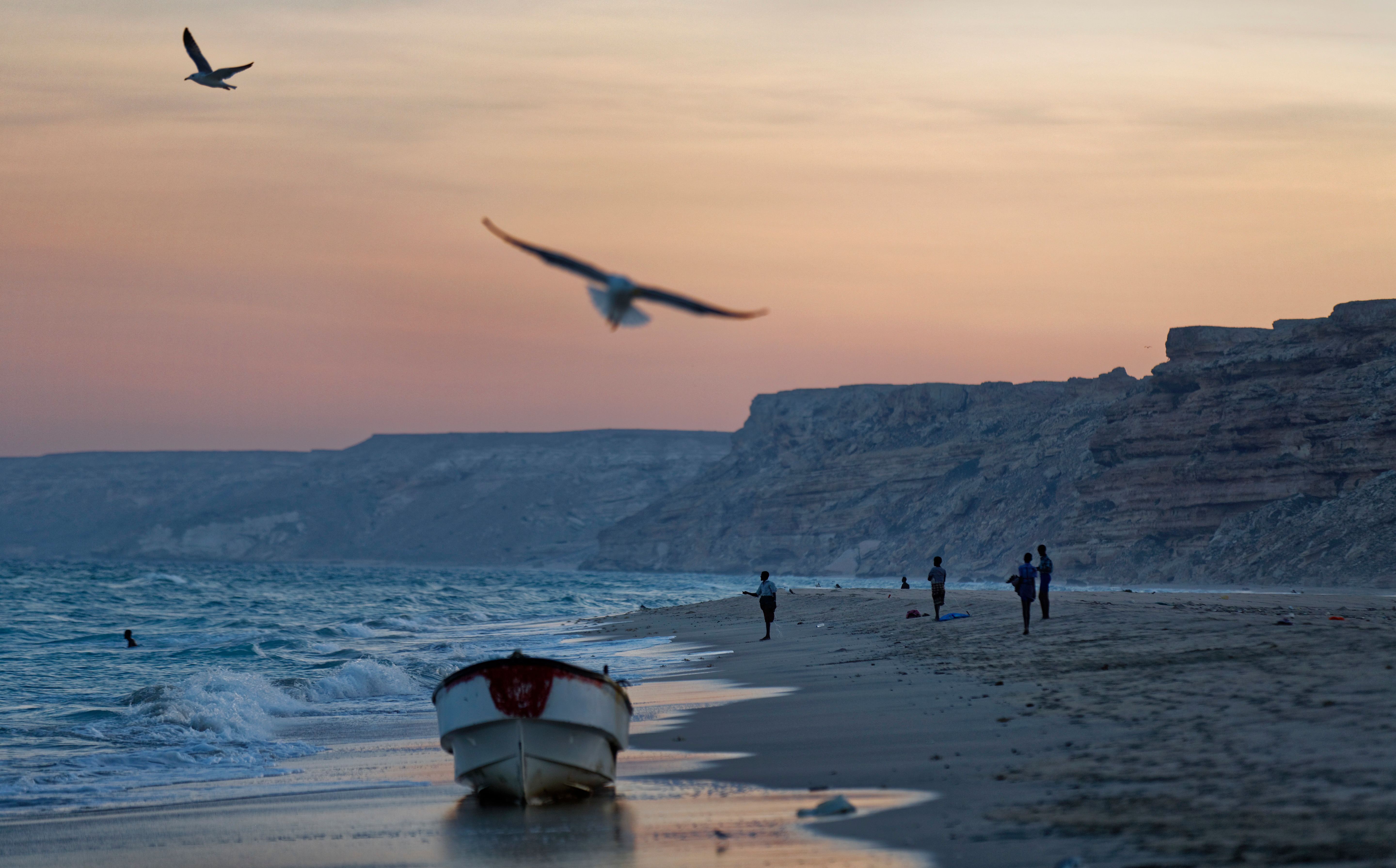 Fishermen stand on the Indian Ocean beach at dusk in the former pirate village of Eyl, in Somalia's semi-autonomous northeastern state of Puntland