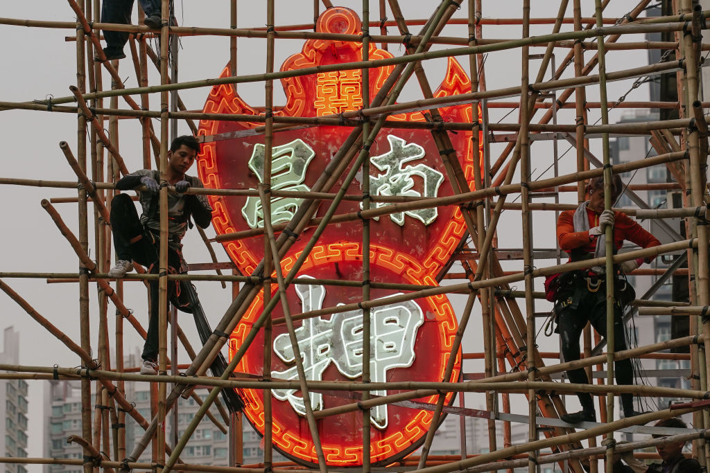 Workers set up bamboo scaffolding in preparation for removing the neon signs of a pawn shop in Sham Shui Po district in Hong Kong