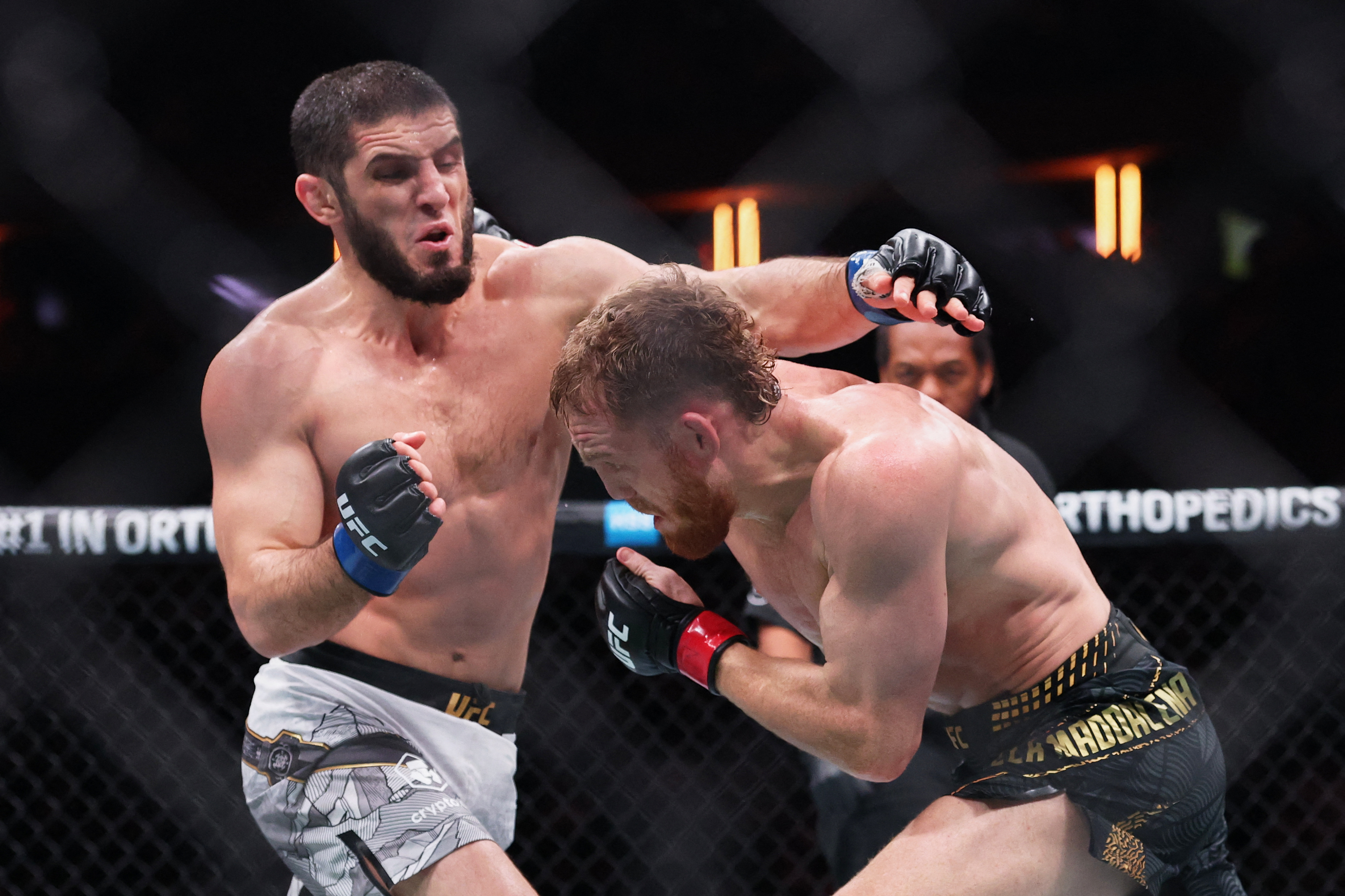 Islam Makhachev (blue gloves) fights Jack Della Maddalena (red gloves).