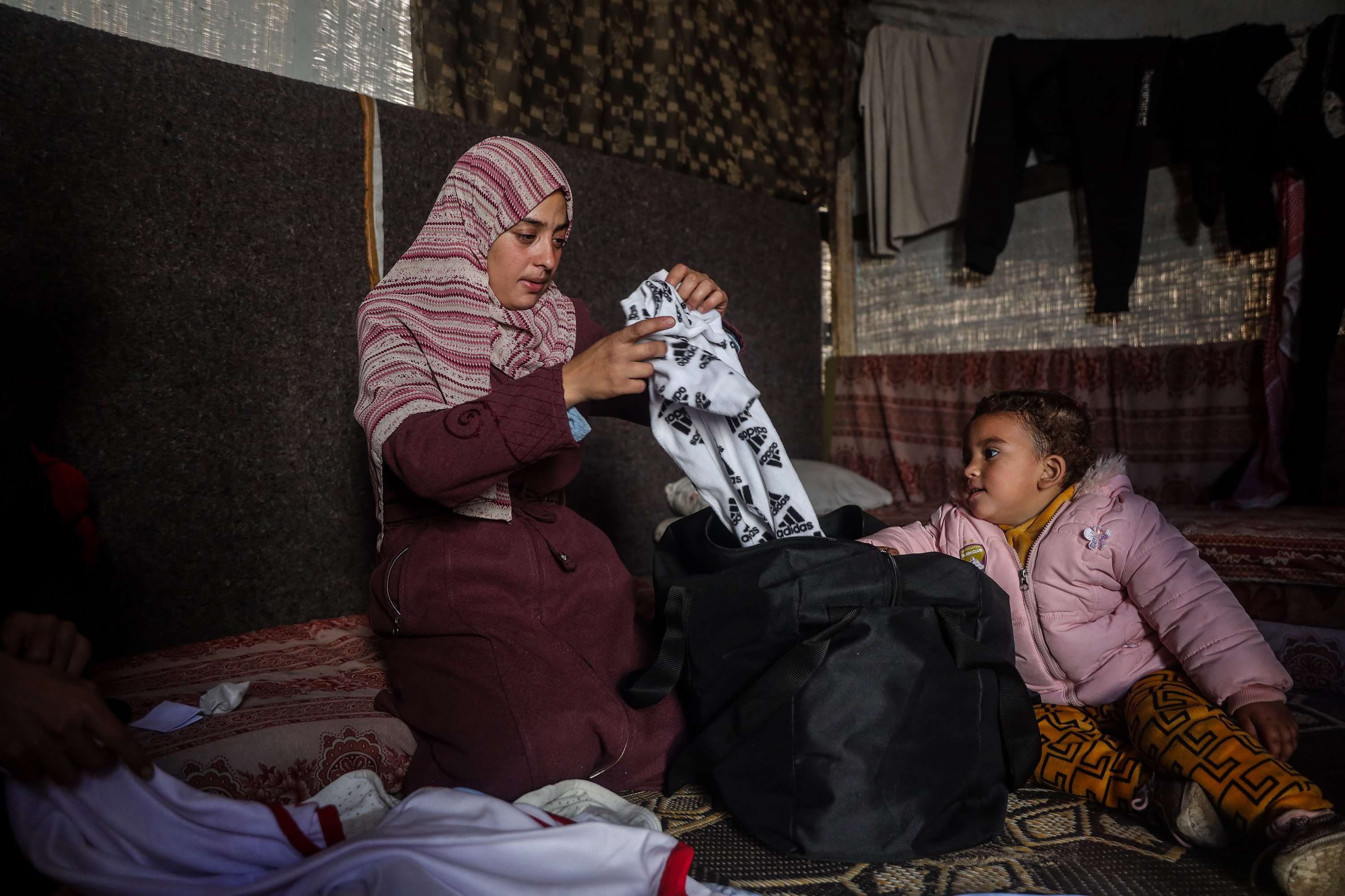 Mother Eman Abu Al-Khair and her two-year-old daughter Mona checking baby Mohammed’s clothes bag after his death